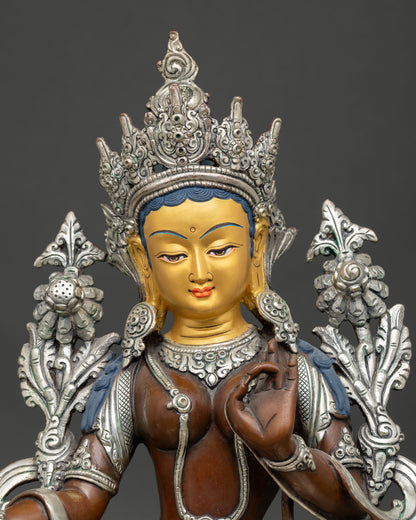 Close up view of Green Tara Buddhist sculpture, showing serene gold painted face and intricate Nepalese craftsmanship