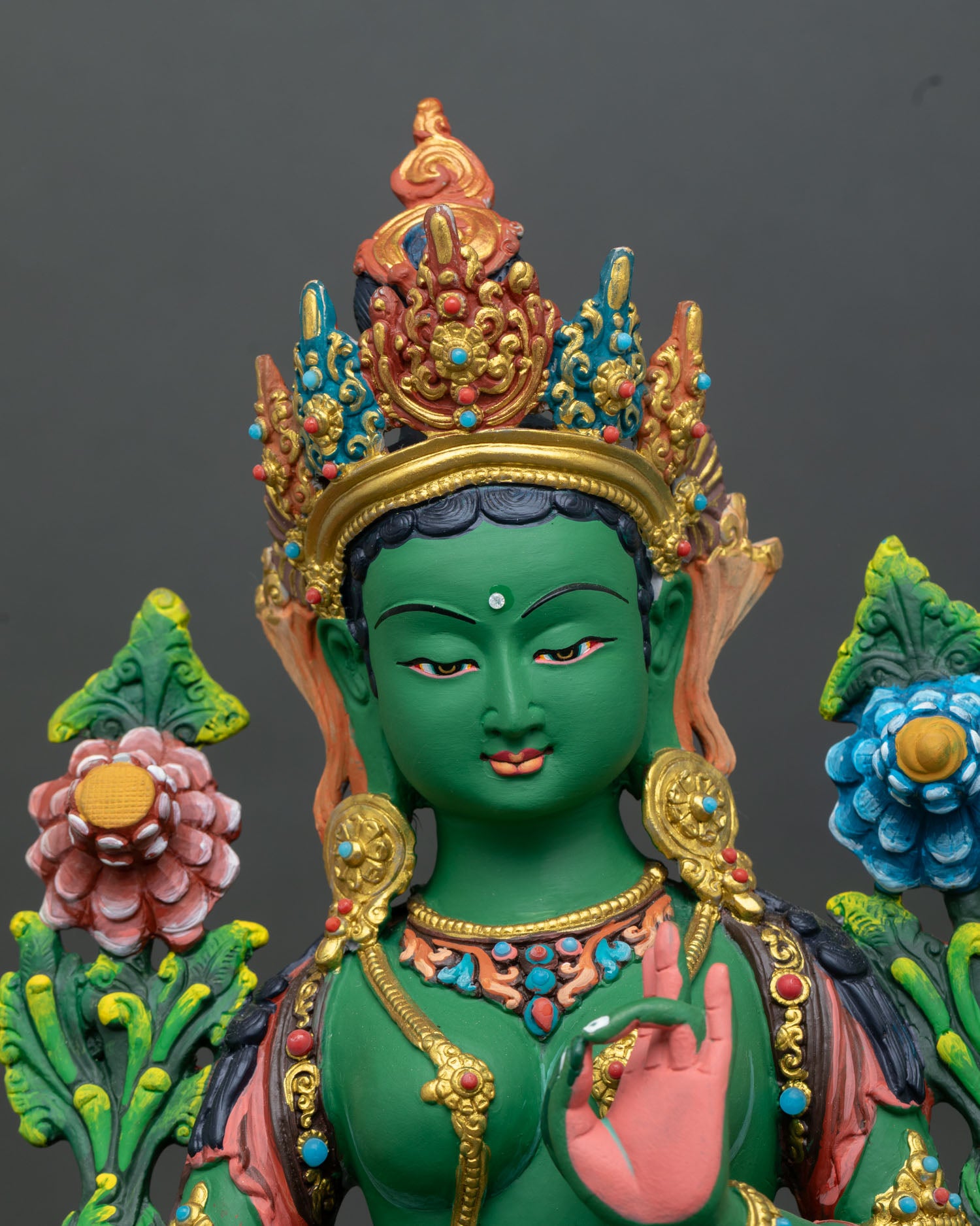 Close up view of Green Tara goddess statue showing serene expression five jewel crown gold details