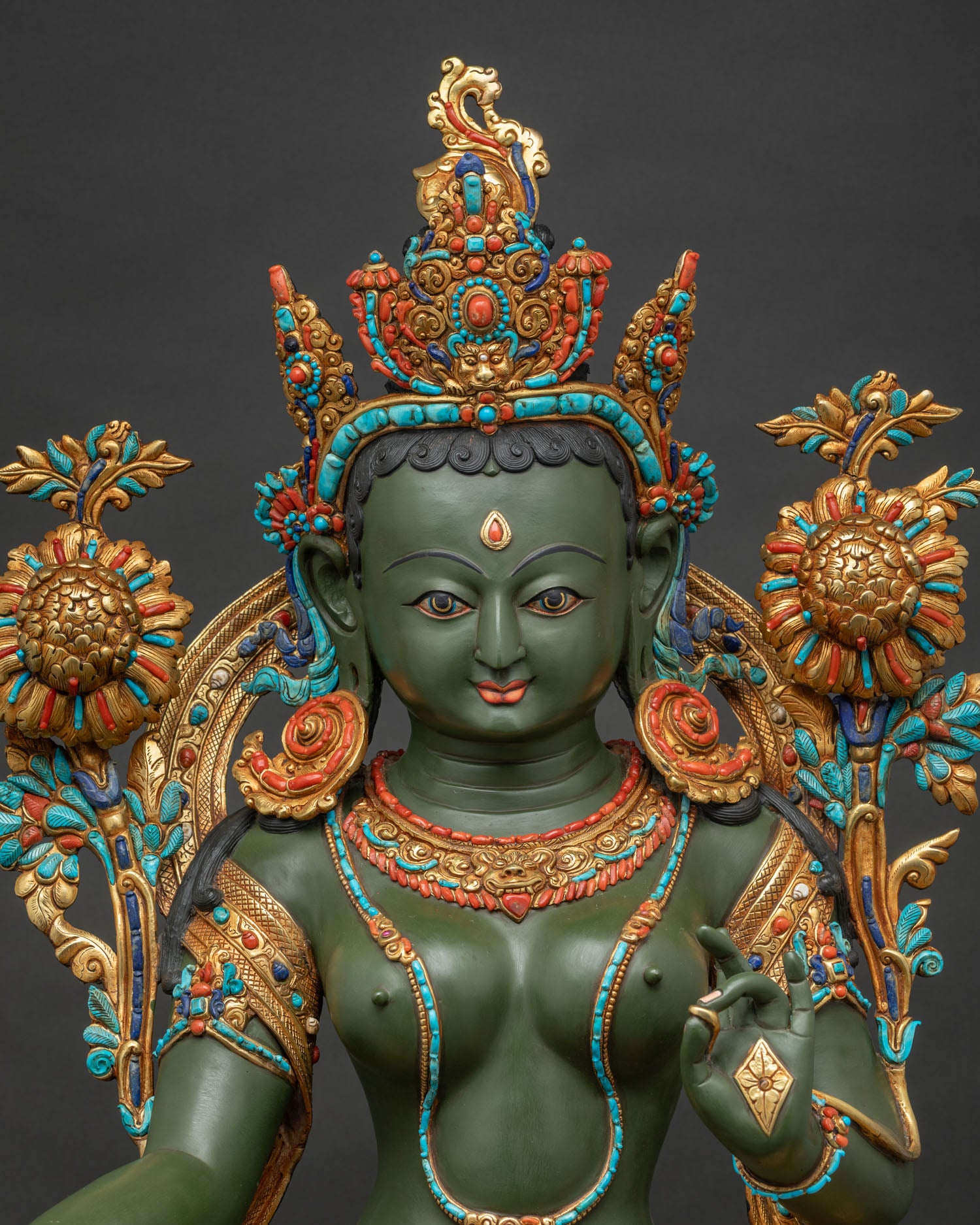 Close up view of Green Tara statue featuring intricate gemstone inlay and detailed Newari gold work.