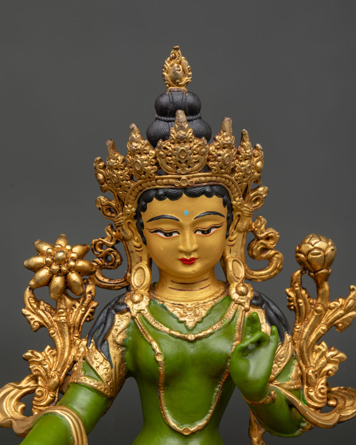 Close up view of Green Tara statue showing 24K gold painted face and gilded details.