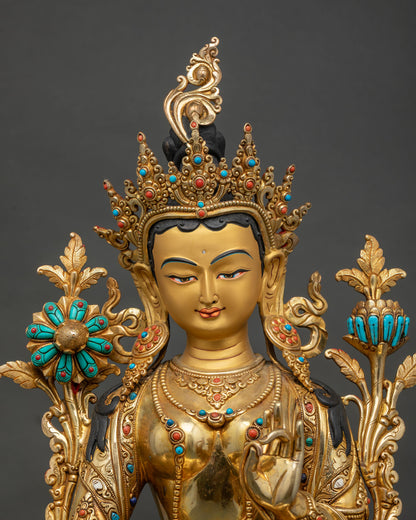 Close up view of Green Tara statue showing gold painted face, turquoise and coral stone inlays.