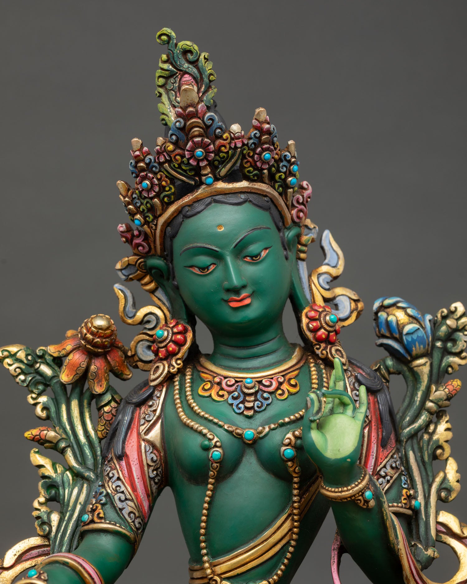 Close up view of Green Tara statue showing serene expression, Abhaya Mudra, and vibrant acrylic color details.