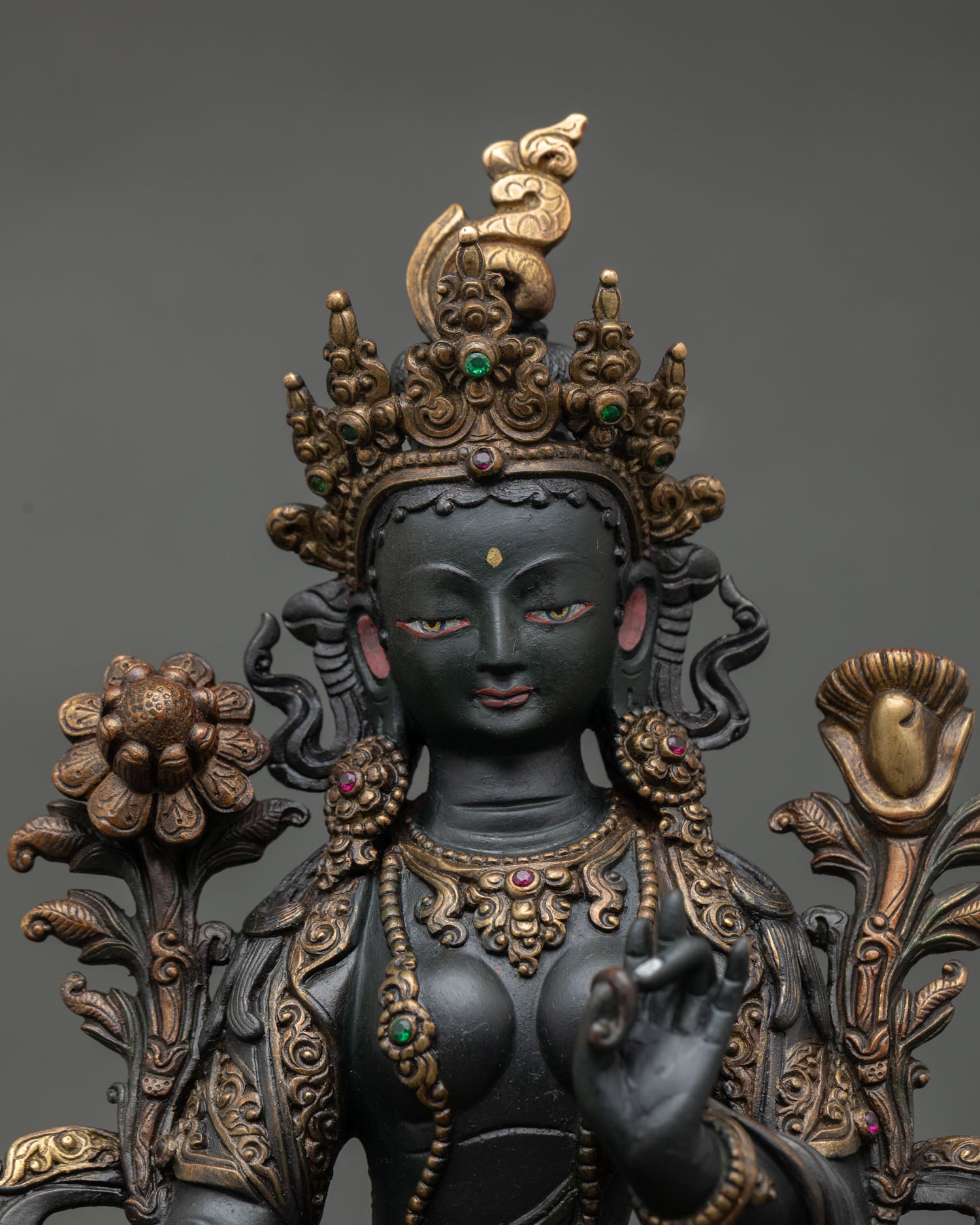 Close up view of Green Tara statue showing serene facial expression detailed craftsmanship and gold accented sacred ornaments.