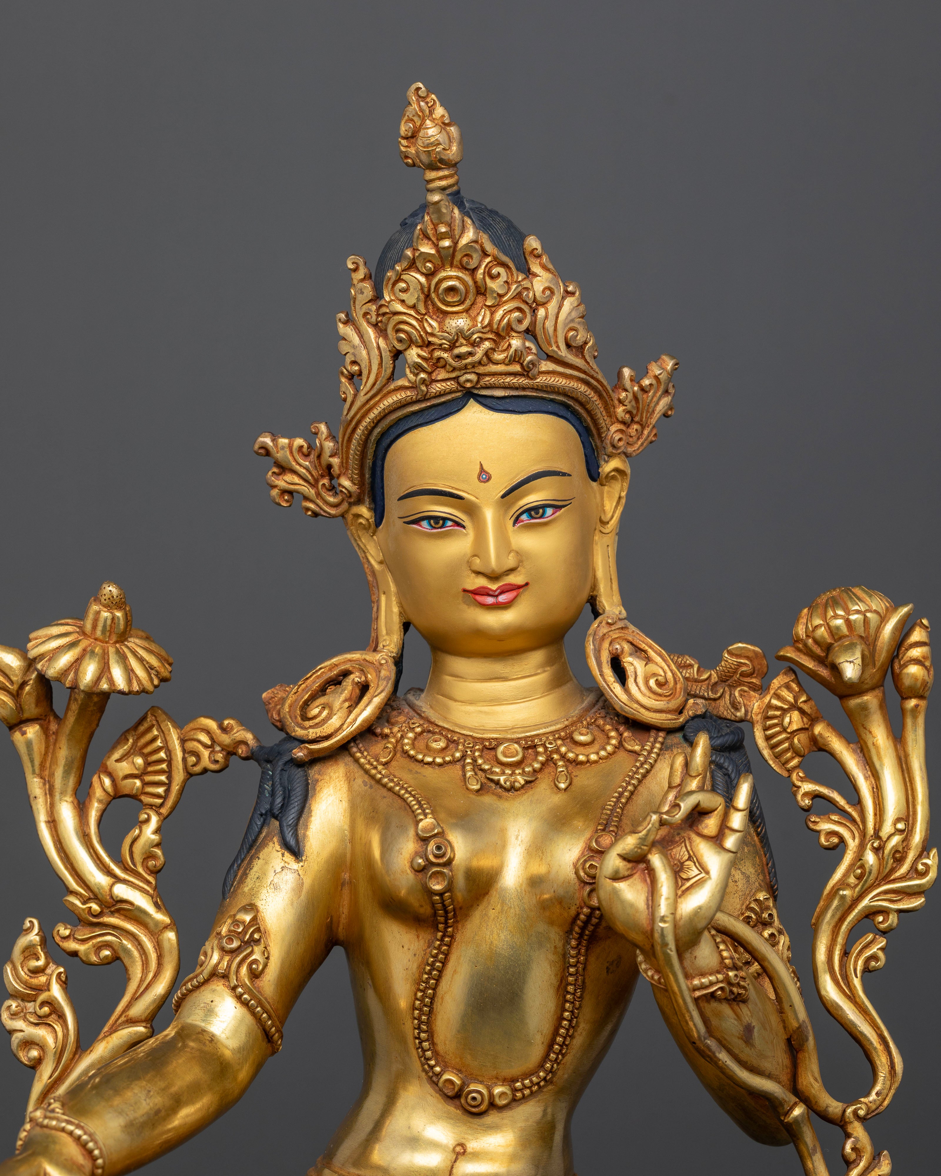 Close up view of Green Tara statue with gold painted face and Varada Vitarka Mudras