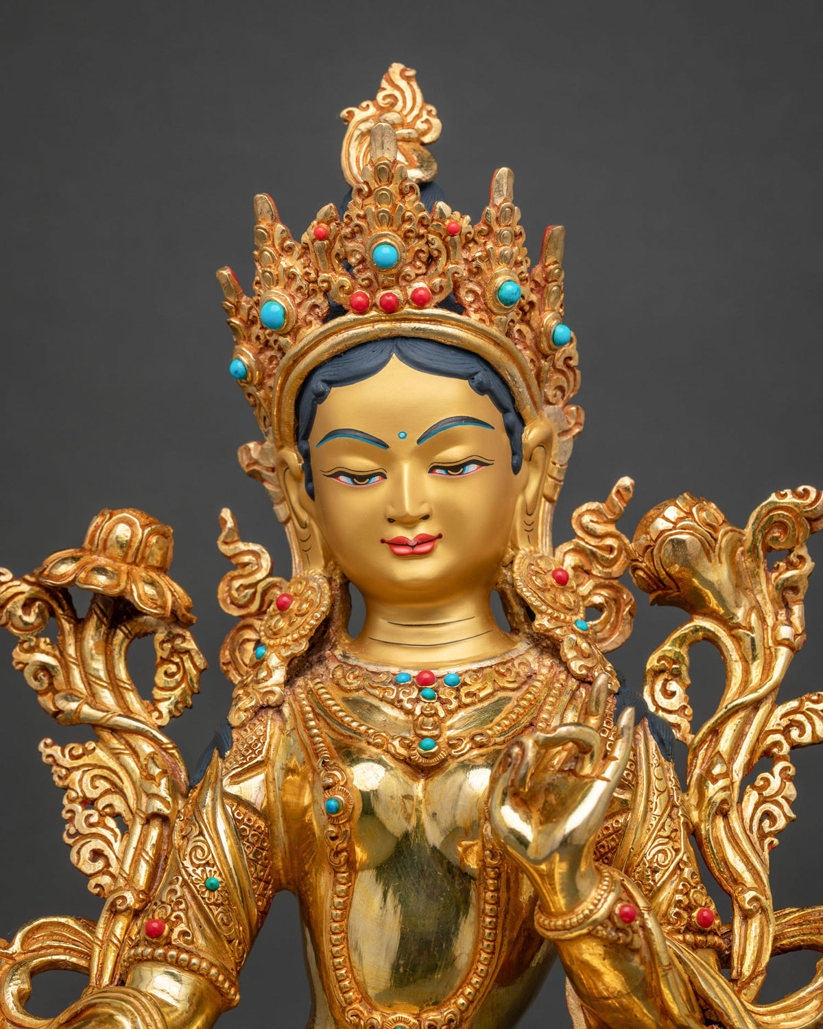Close up view of Green Tara Statue with serene gold painted face and ornate crown