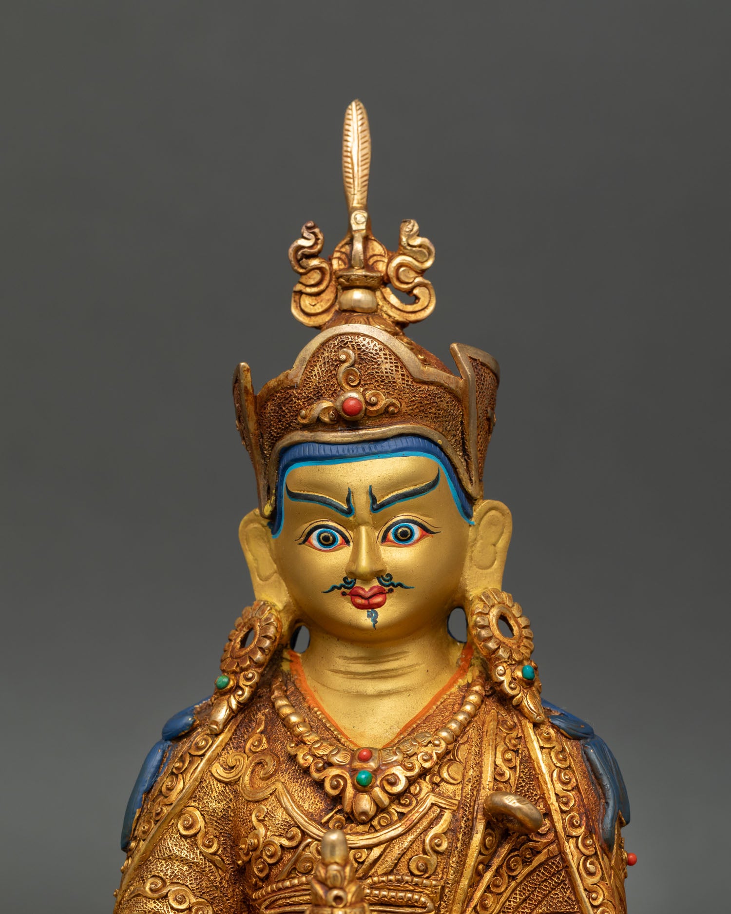 Close up view of Guru Rinpoche statue showing gold painted face serene expression and detailed Himalayan craftsmanship