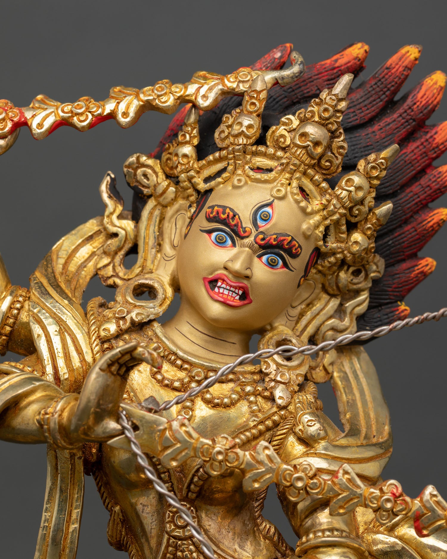 Close up view of Kurukulla statue with luminous gold painted face symbolizing magnetizing energy transformation and enlightened tantric wisdom