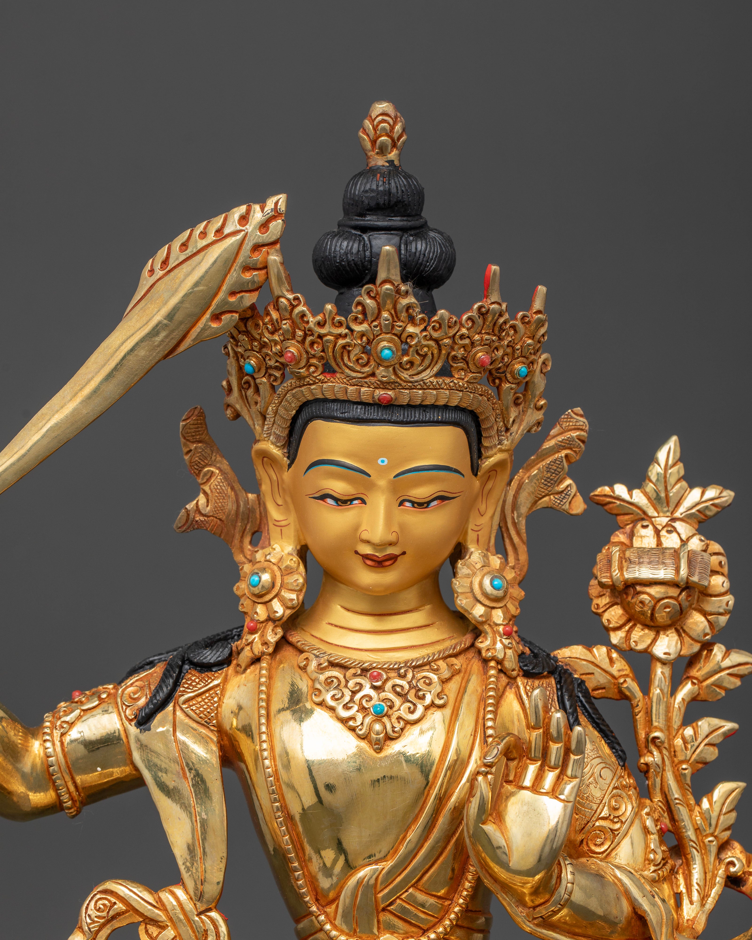 Close-up view of Manjushri Statue highlighting the flaming sword, utpala flower, and intricate floral carvings