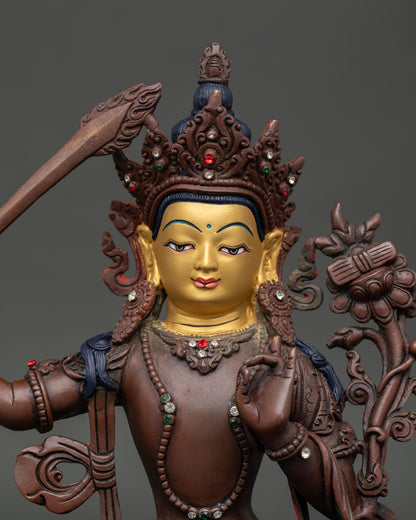 Close up view of Manjushri statue showing gold painted face gemstone adornments and intricate details.