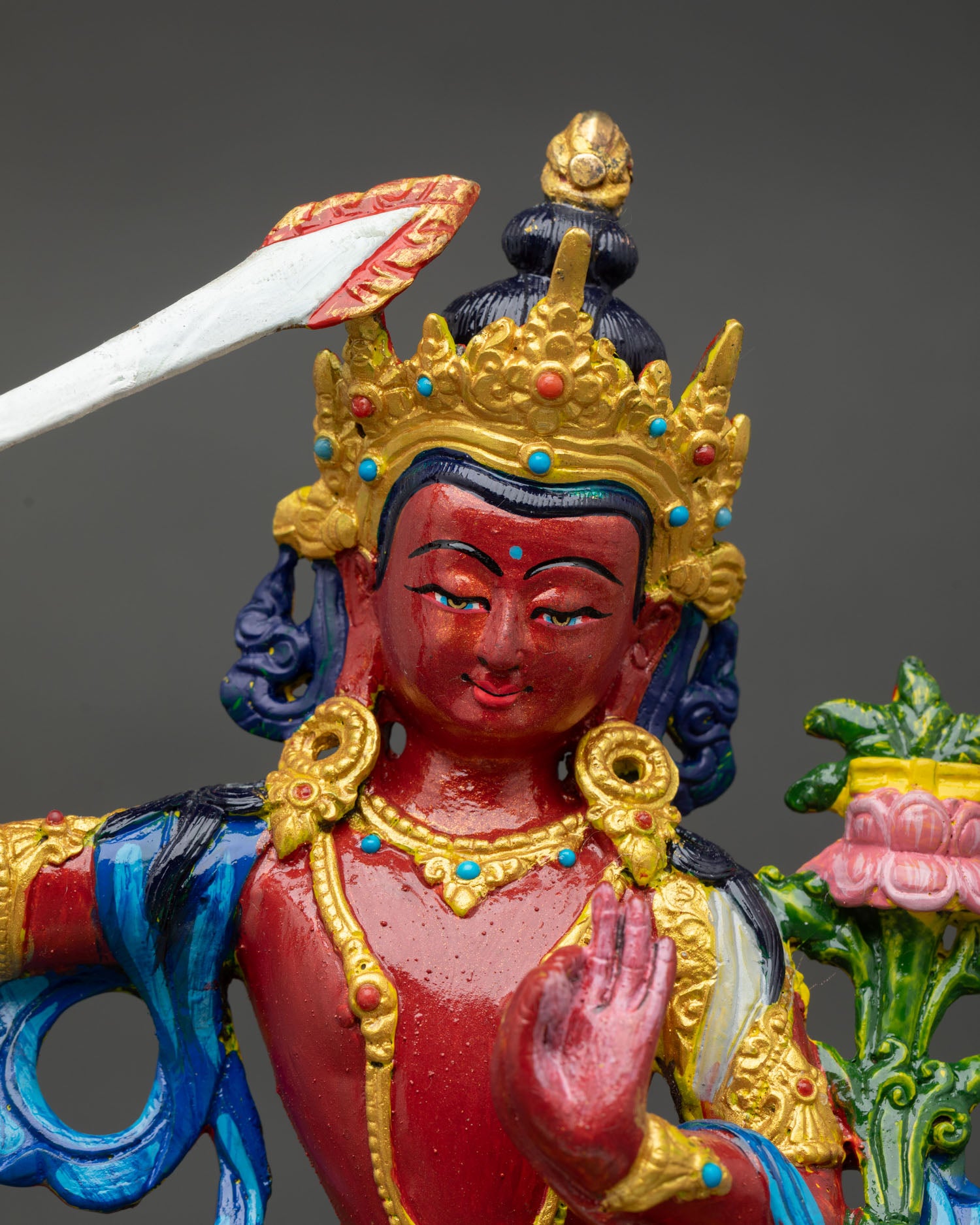 Close up view of Manjushri statue showing serene expression detailed facial features and symbolic wisdom sword and sacred ornaments.