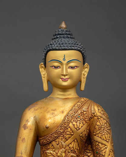 Close up view of Medicine Buddha sculpture showing detailed gold engraved robes
