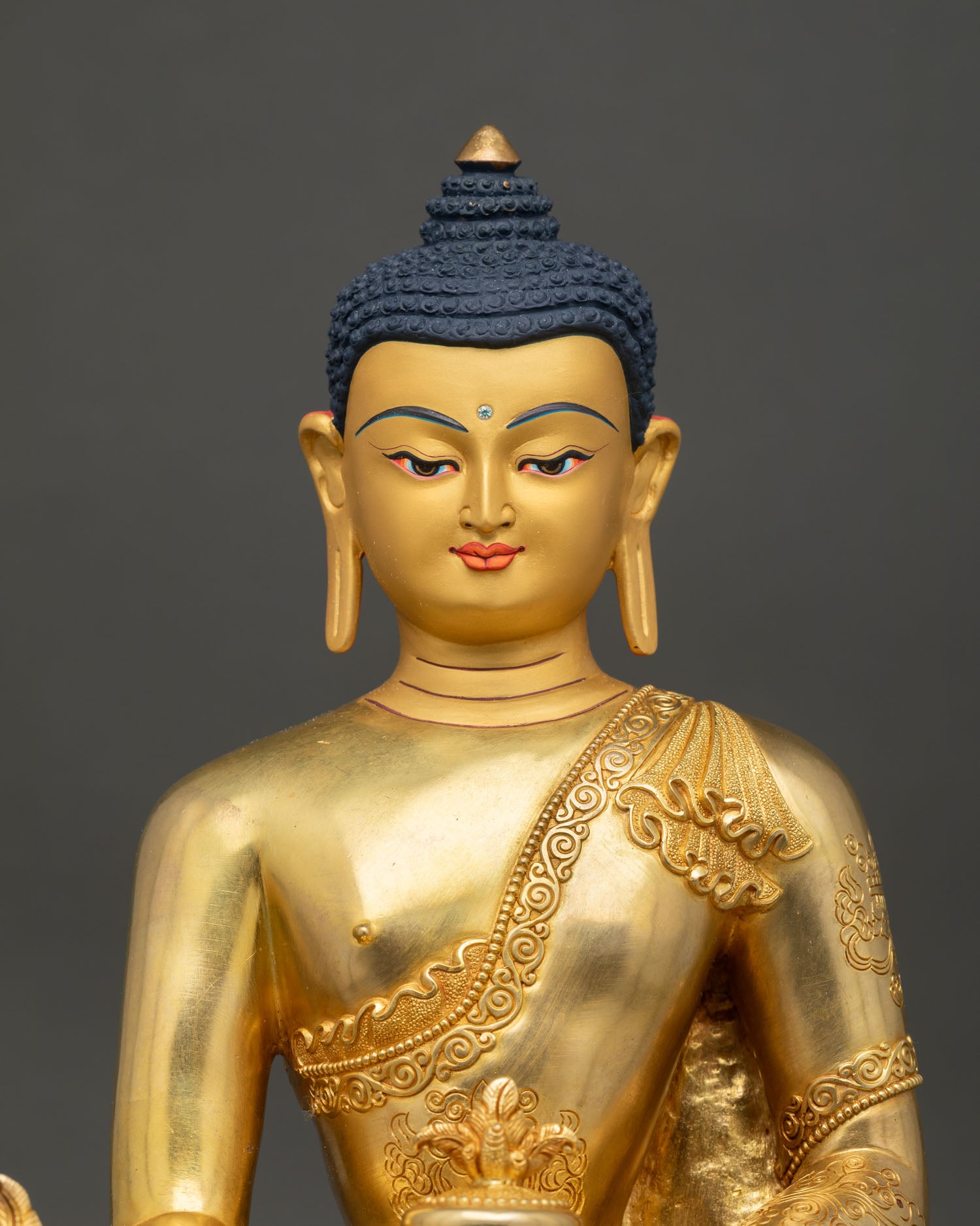 close up view of medicine buddha statue with 24k gold gilded details and serene expression