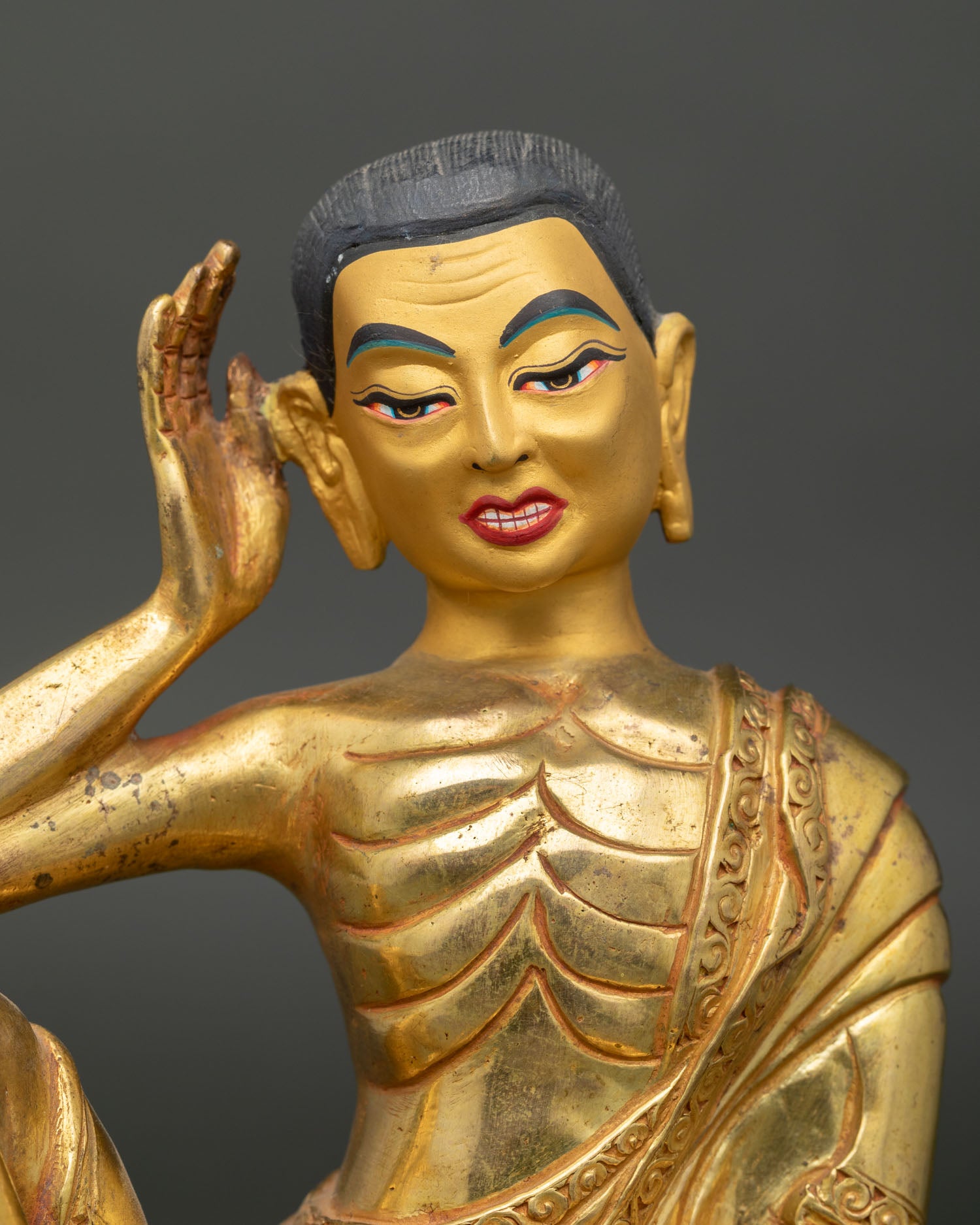 Close Up View of Milarepa Statue with Gold Painted Face and Flowing Gilded Robes