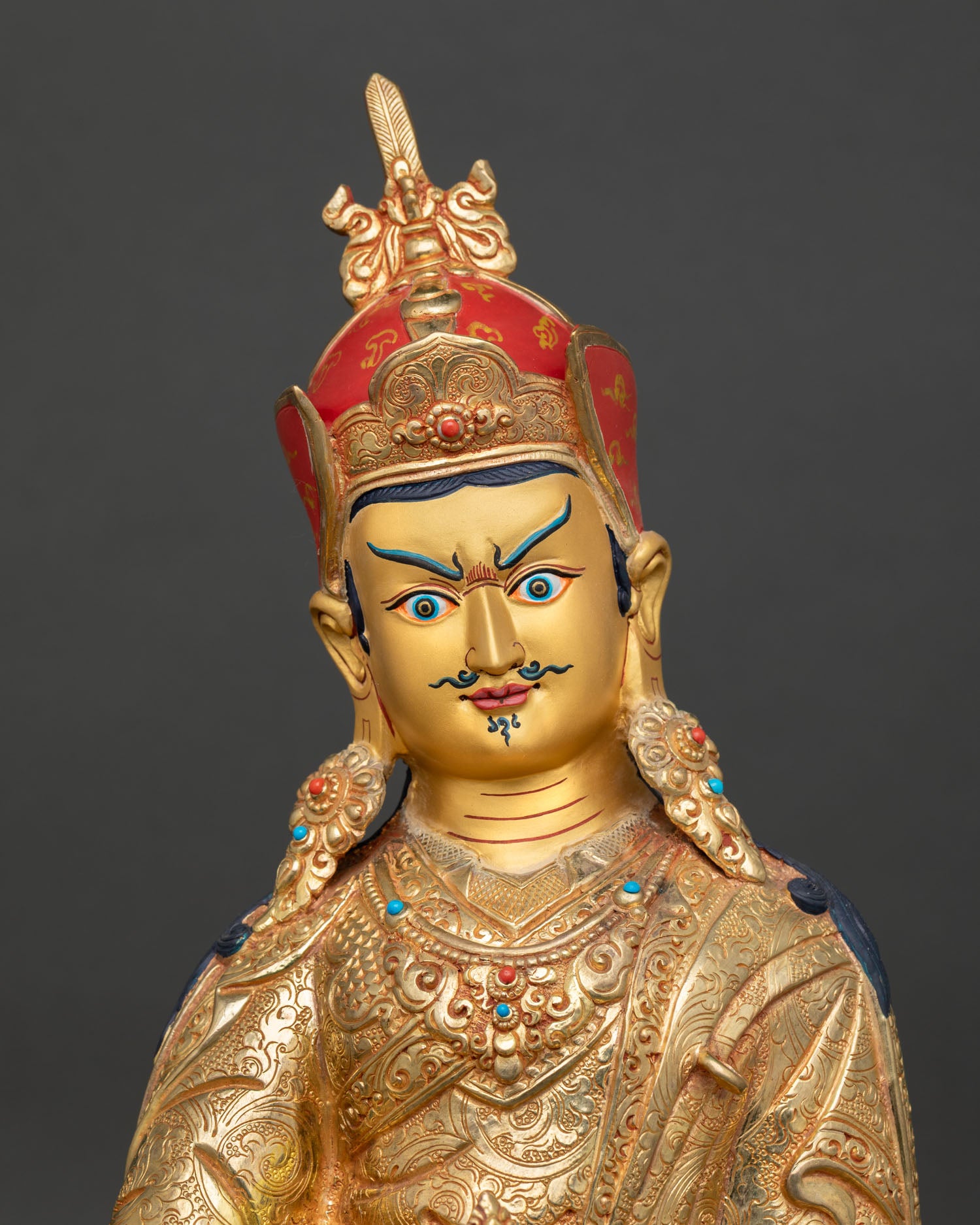 Close up view of Padmasambhava Guru Rinpoche sculpture, showing serene golden face ornate crown and gemstone details
