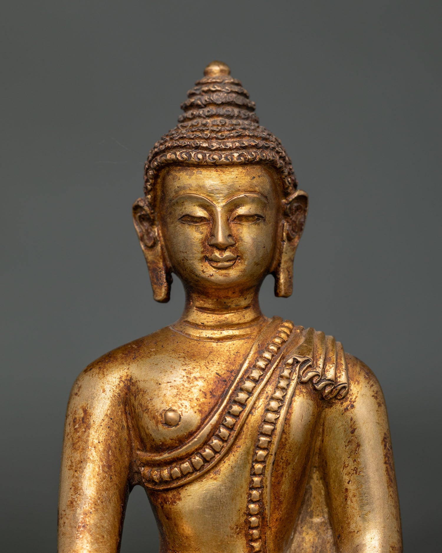 Close up view of Shakyamuni Buddha face and hand carved monk robe details with antique finish.