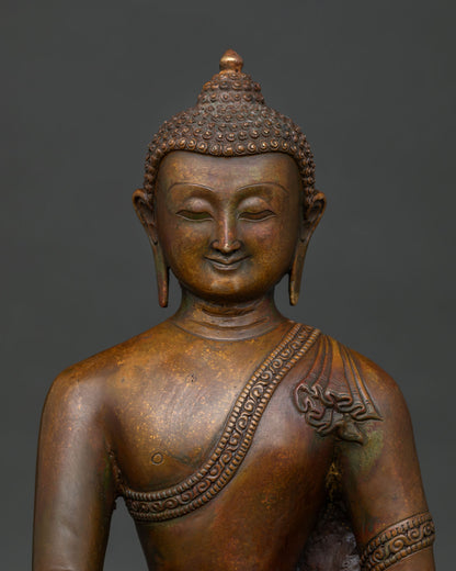 Close up view of Shakyamuni Buddha face with detailed monastic robe carving and antique copper finish.