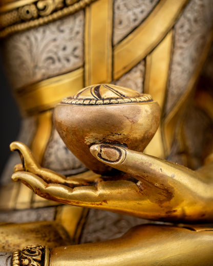 Close-up view of Shakyamuni Buddha left hand holding patra bowl showing detailed copper craftsmanship with gold fire gilded finish and sacred Vajrayana symbolism
