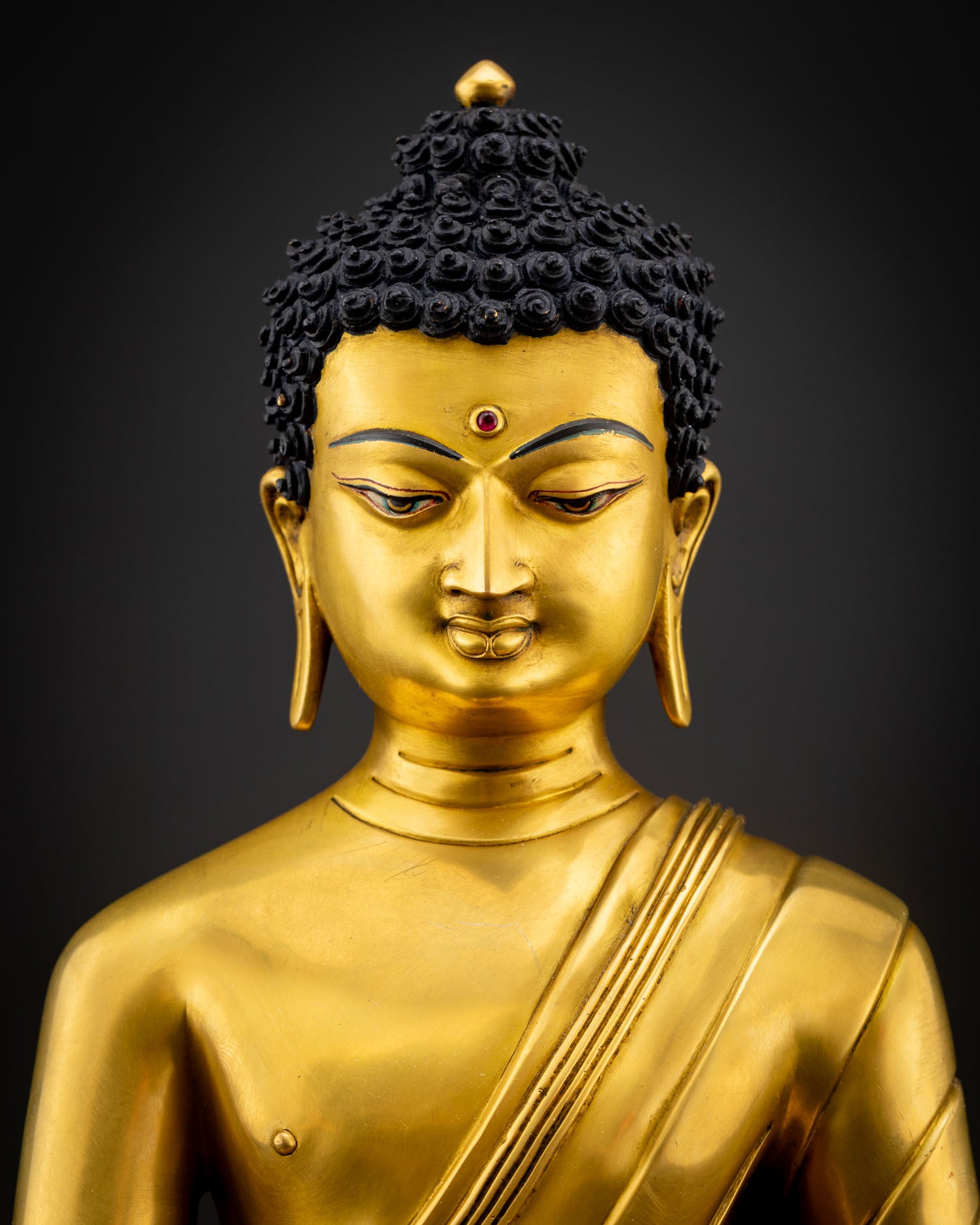 Close up view of Shakyamuni Buddha sculpture showing detailed carvings gold gilded surface texture and calm meditative facial expression