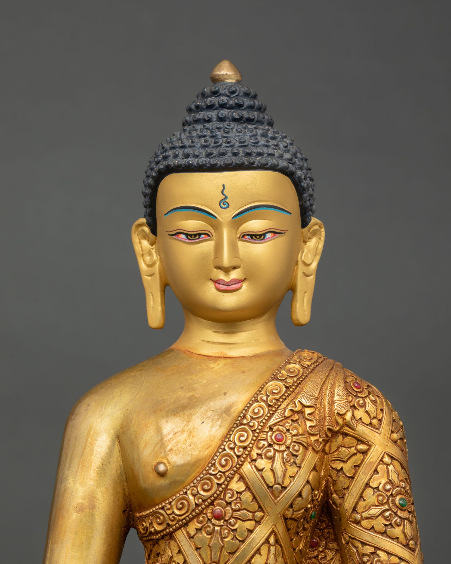 Close up view of Shakyamuni Buddha sculpture showing earth witness gesture alms bowl detailed floral scroll robes and semi precious stone accents on sacred Buddhist statue
