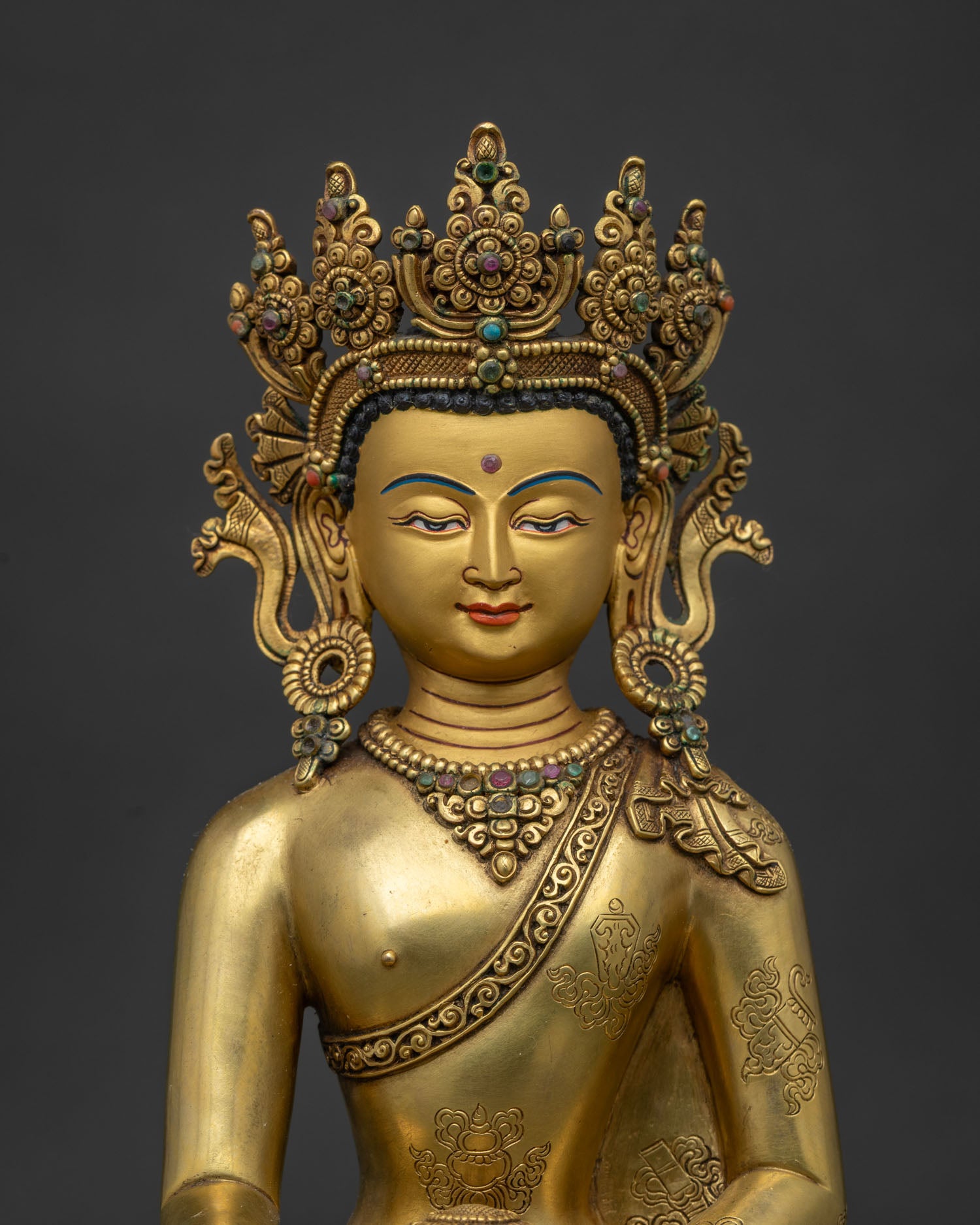 Close up view of Shakyamuni Buddha statue showing serene gold painted face and detailed crown