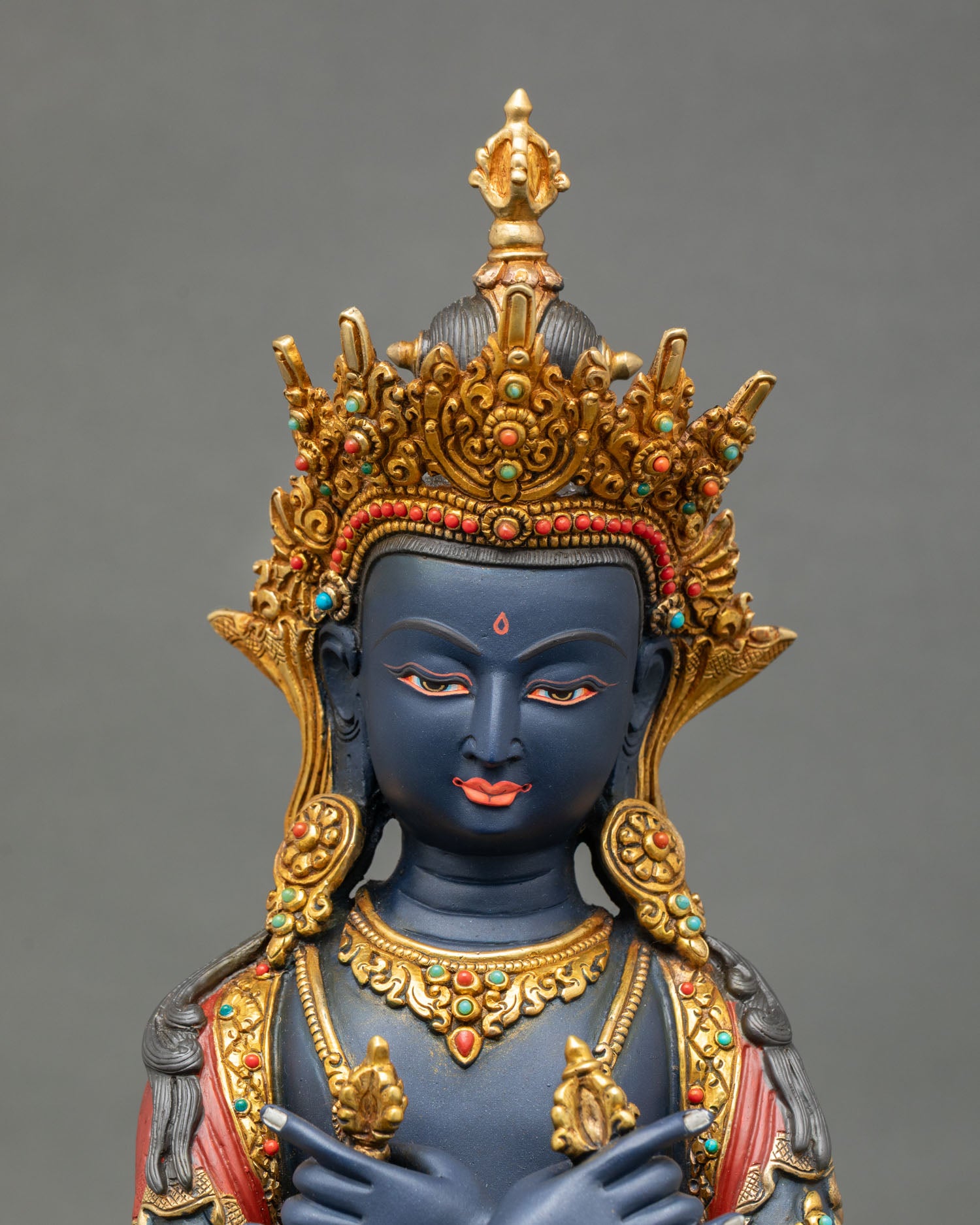 Close up view of Vajradhara sculpture showing gold painted face, five jeweled crown with semi precious stones, and detailed Himalayan Newari craftsmanship