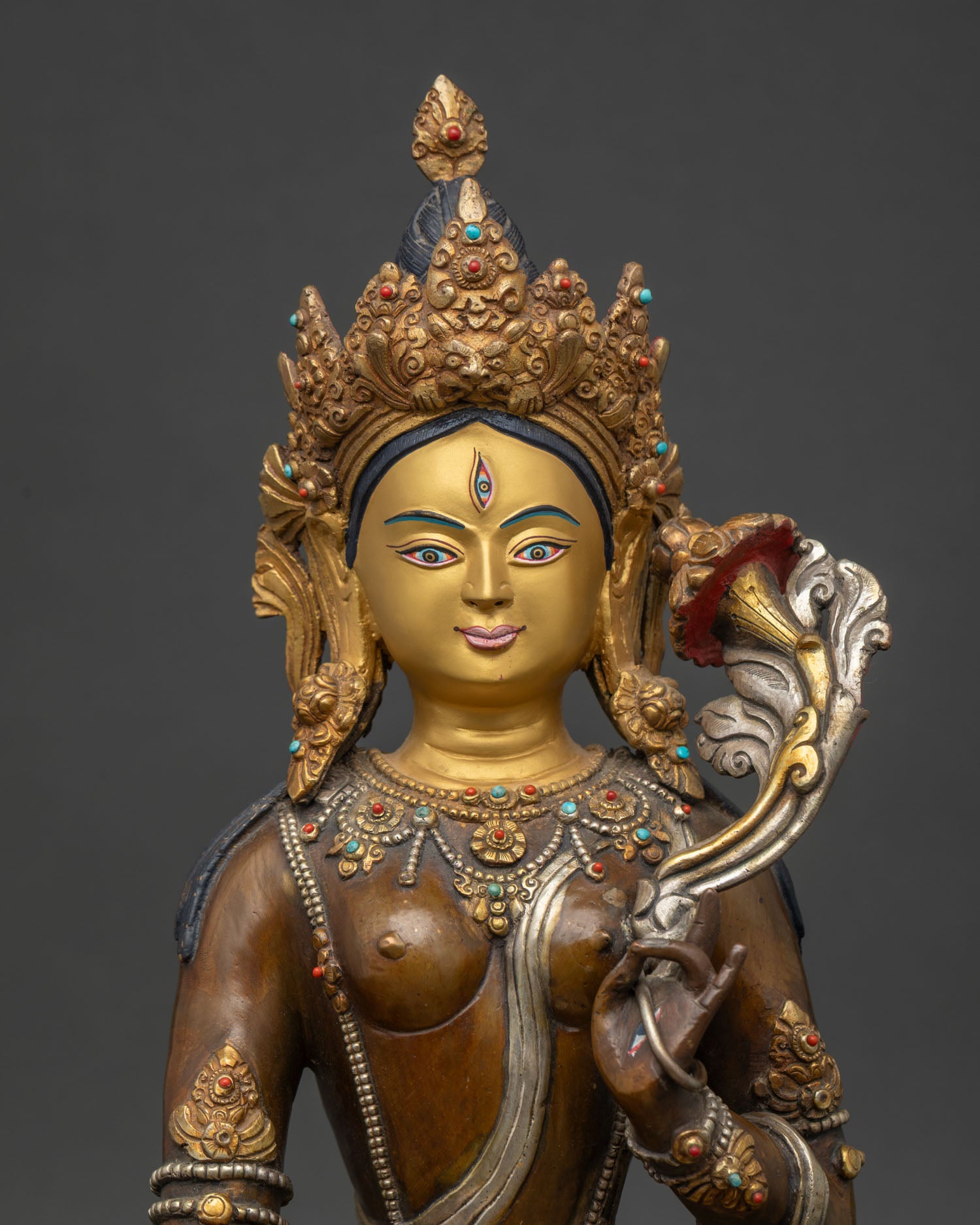 Close up white tara face with seven eyes and intricate five jewel crown.