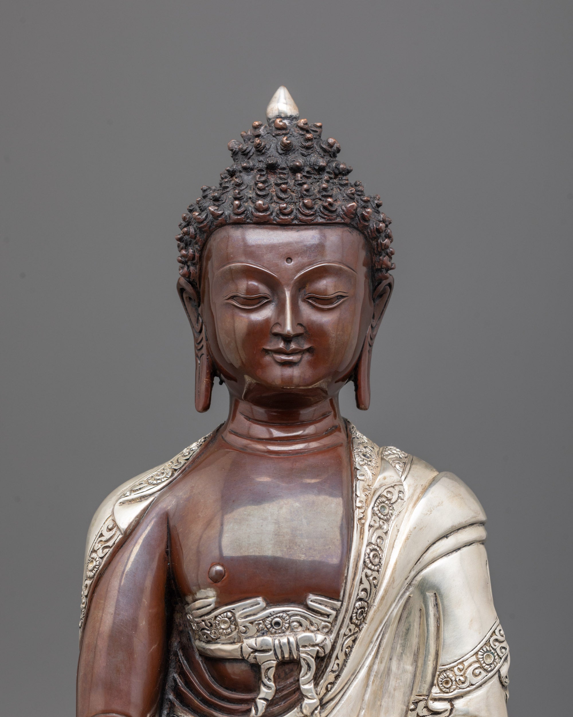 close-up of Gautama Buddha face with oxidized copper and detailed silver-plated robe