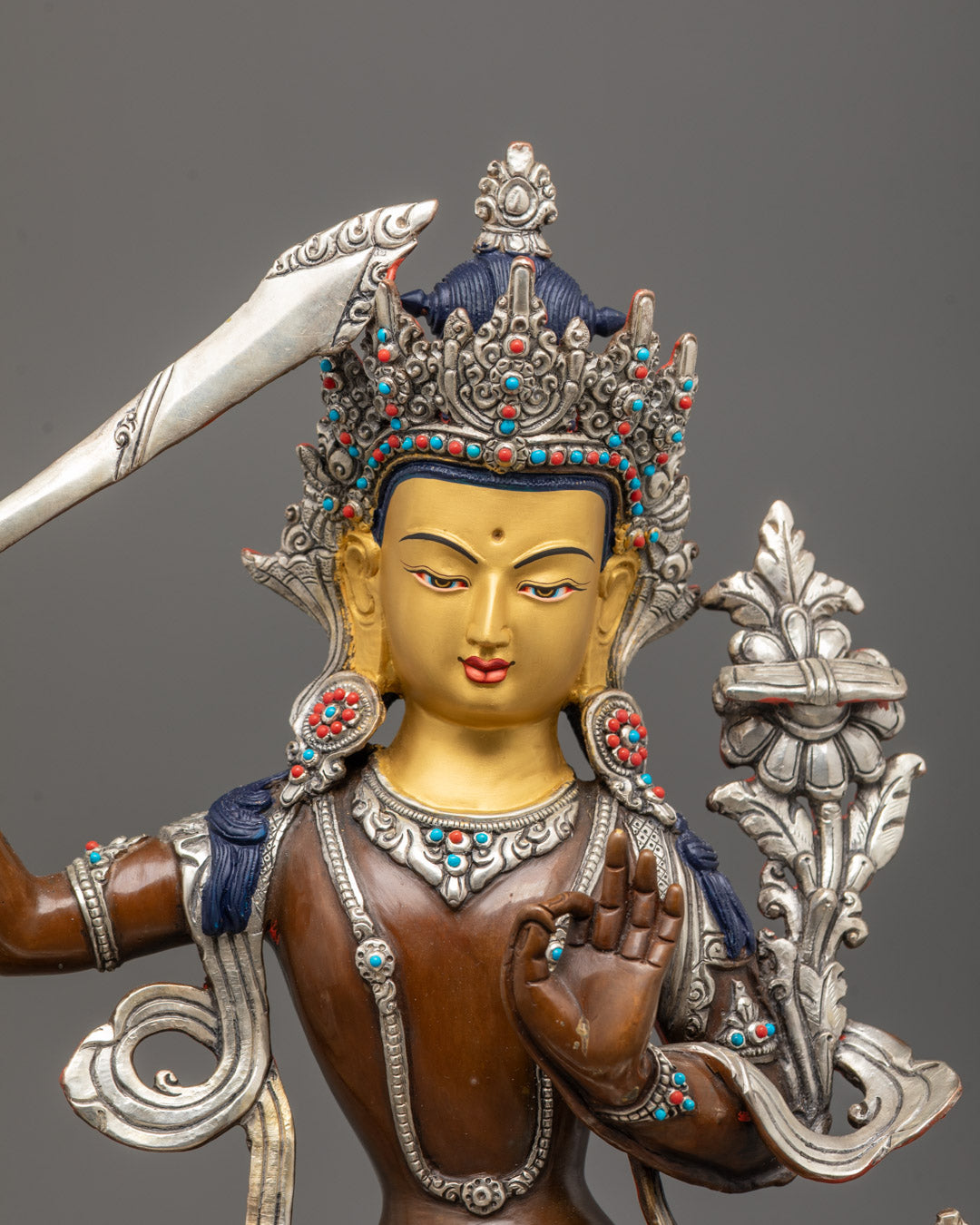 close-up of Manjushri’s gold-gilded face, crown, and flaming wisdom sword details
