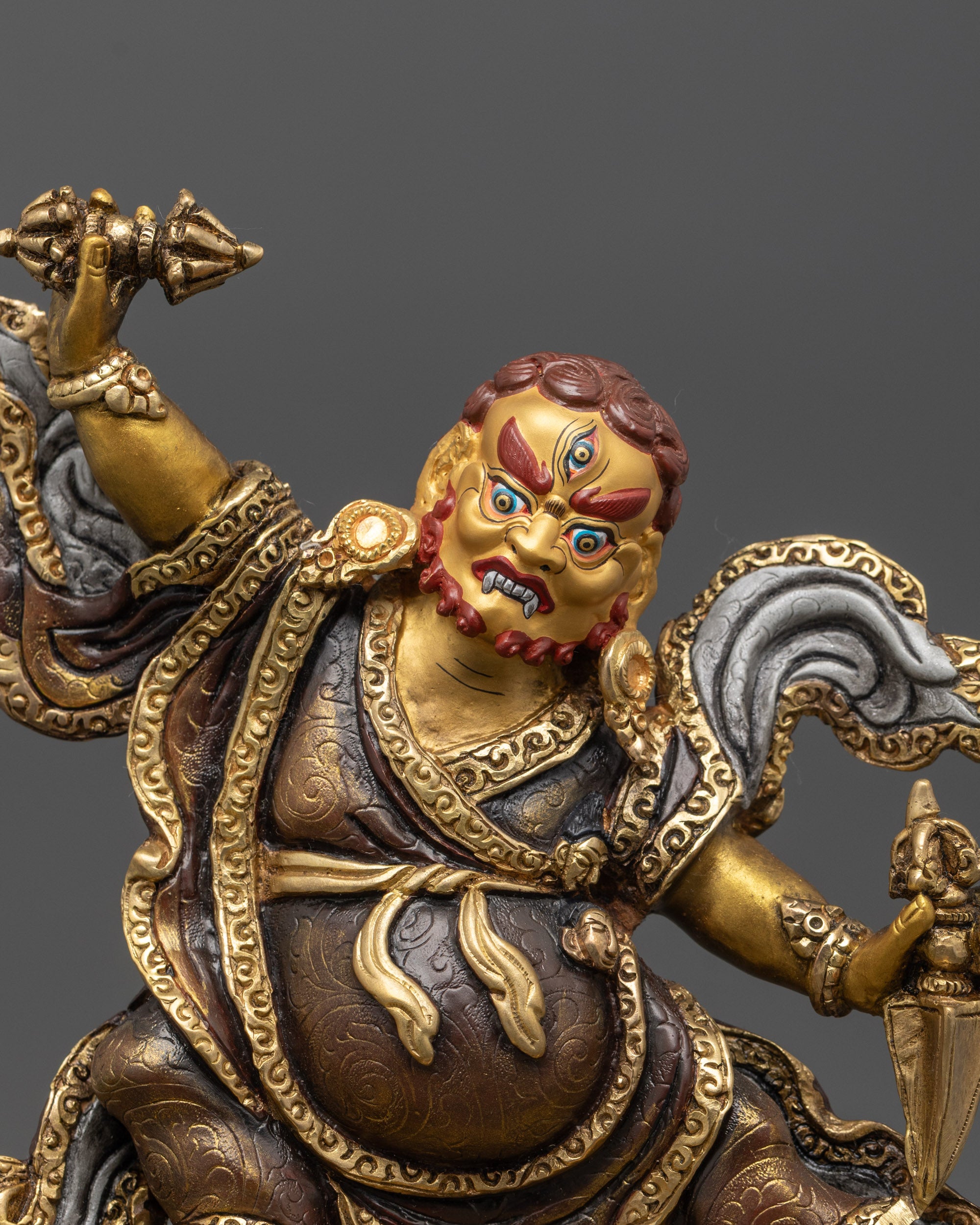 close-up of dorje drolo statue face with gold gilding and wrathful expression
