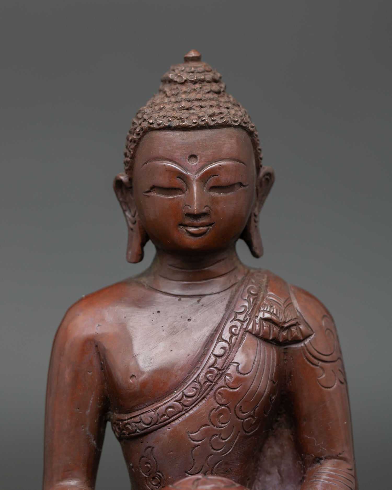 Close view of Amitabha Buddha sculpture showing detailed monk robe carving serene expression and antique copper texture.