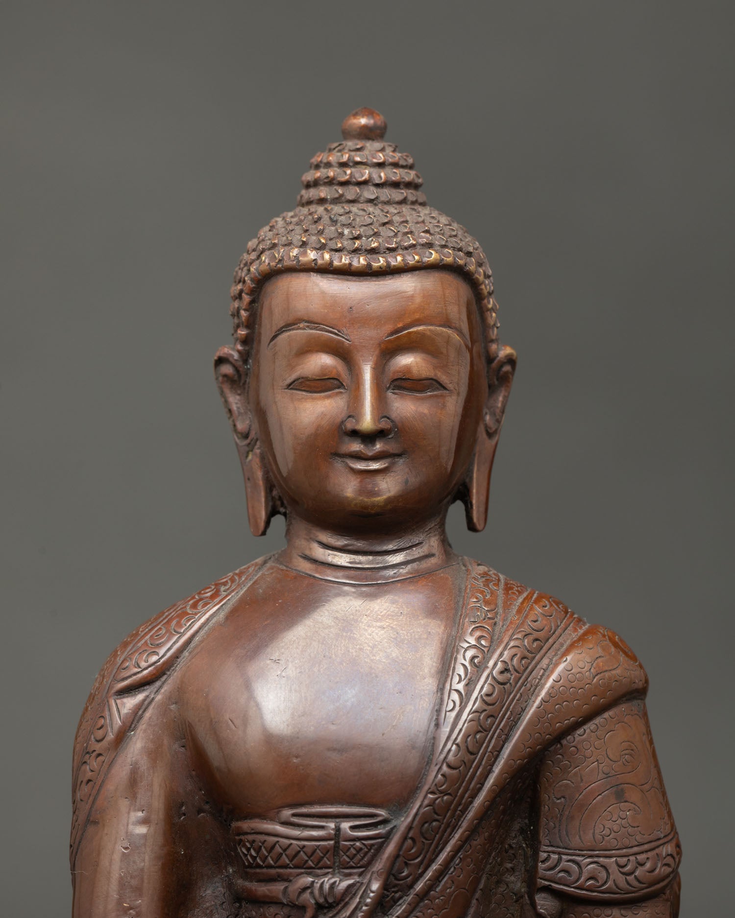 Close view of Shakyamuni Buddha face showing serene expression, intricate Nepalese metalwork, and spiritual Buddhist artistry.