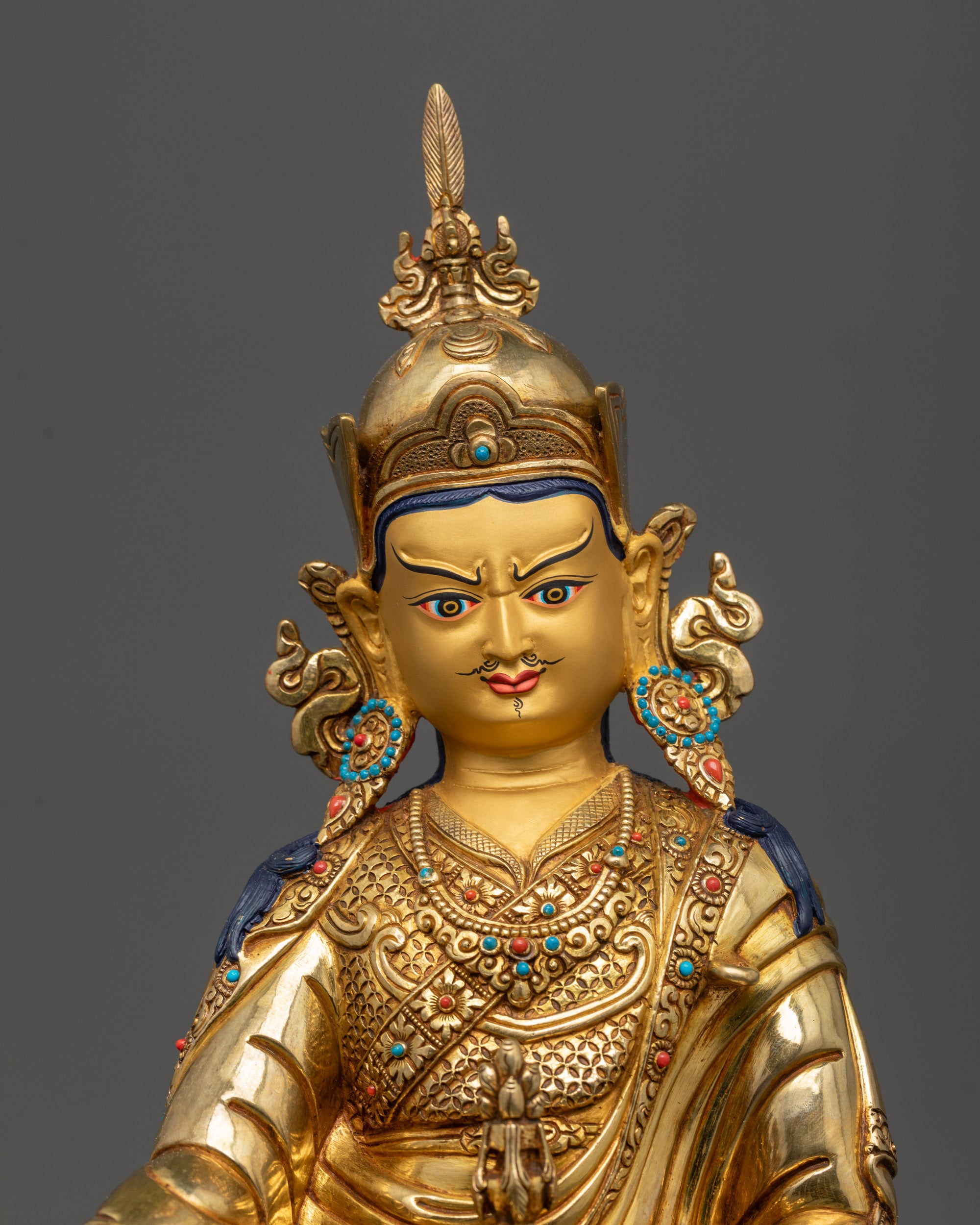 close up Guru Rinpoche statue showing vajra skull cup lotus hat and semi precious stones

