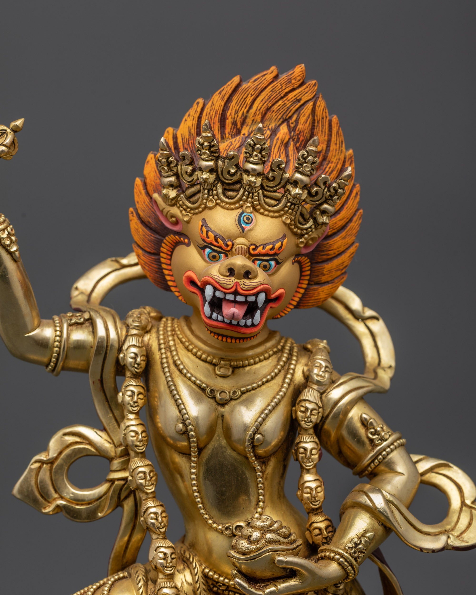 close up Lion-Faced Dakini Simha Mukha gold fire-gilded face and five-skull crown
