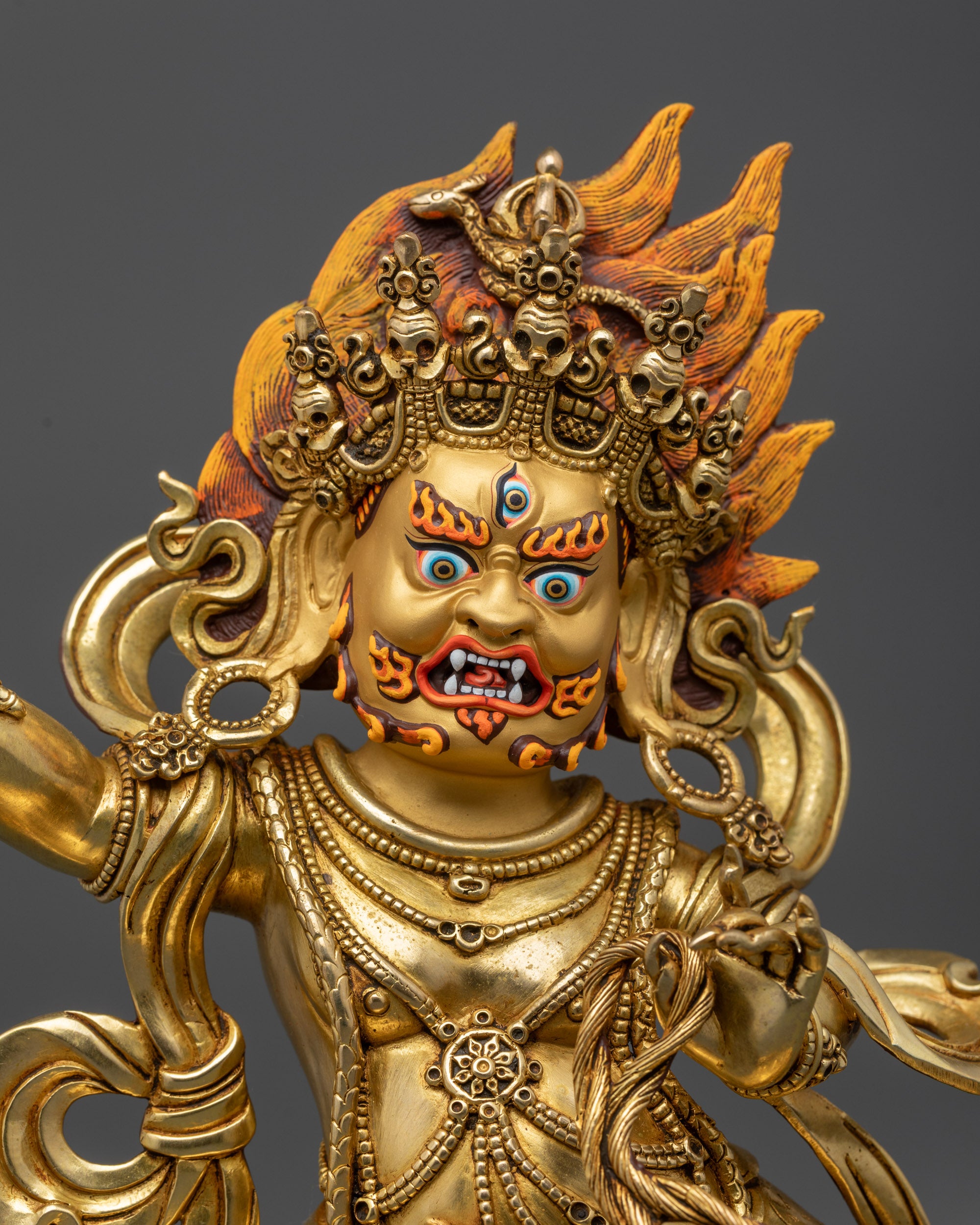 close up Vajrapani statue with third eye crown robe and serpent details
