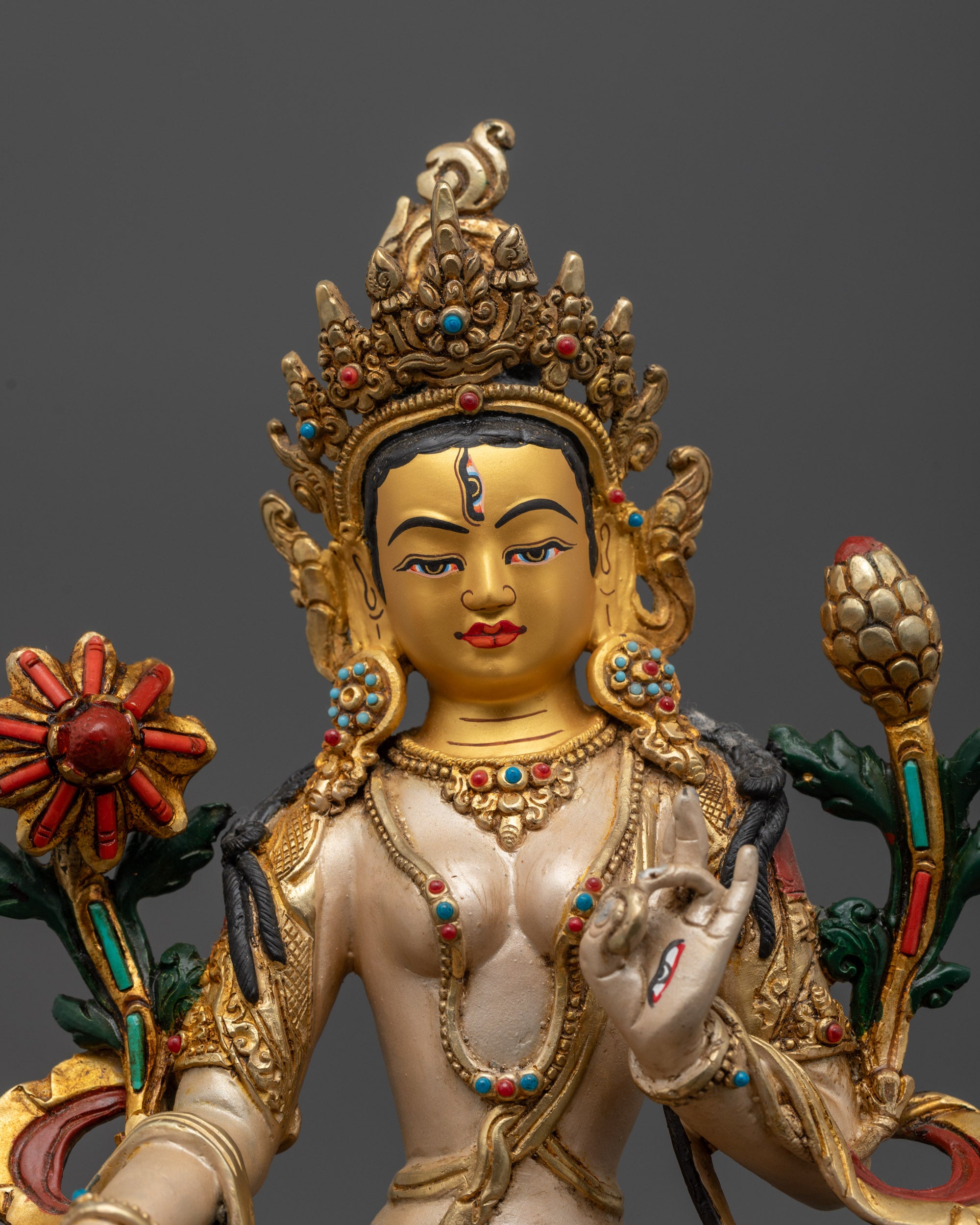 close up White Tara statue with seven eyes and gold-plated utpala flower
