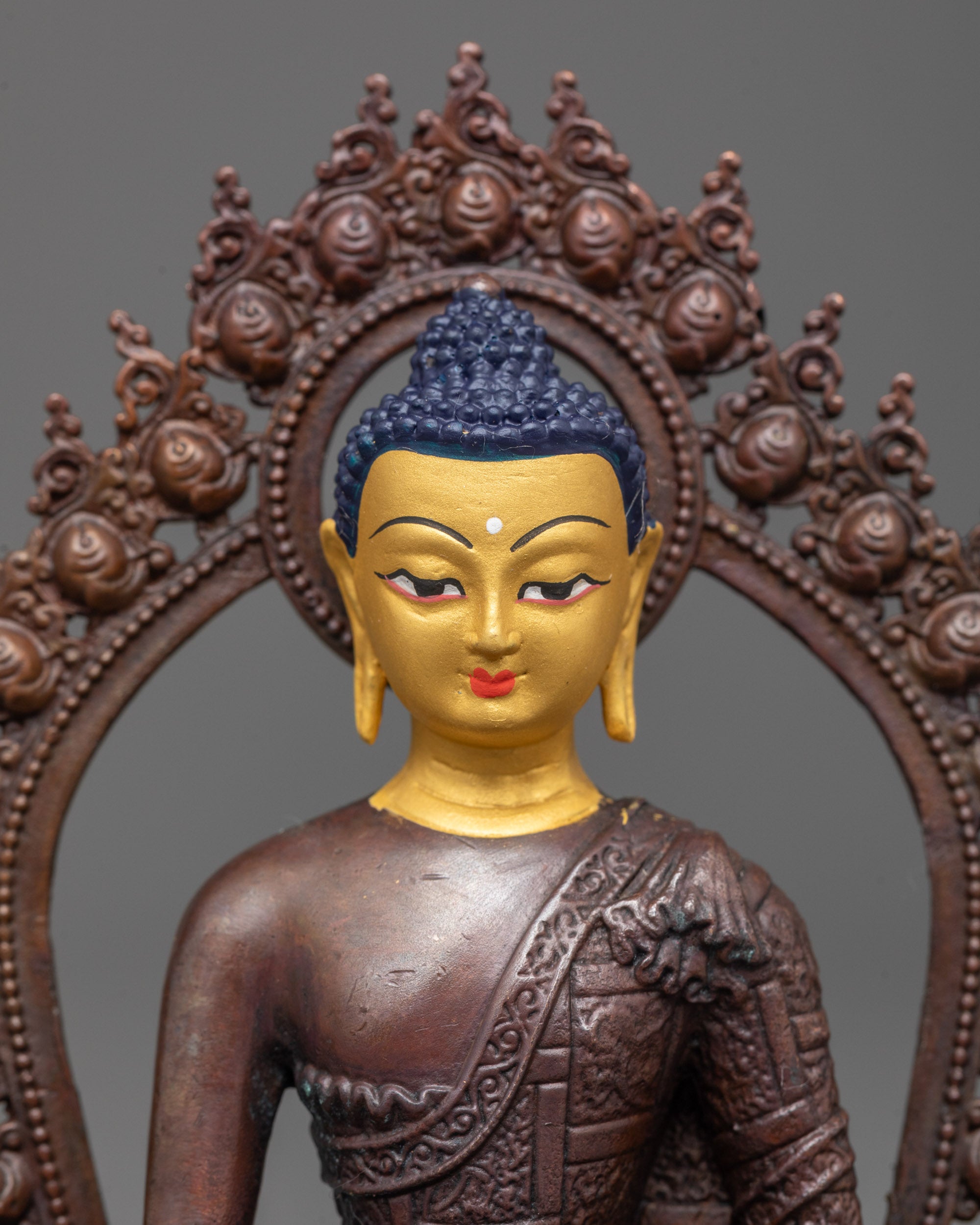 close up of Buddha Shakyamuni statue face showing gold plating and detailed monk robes pattern