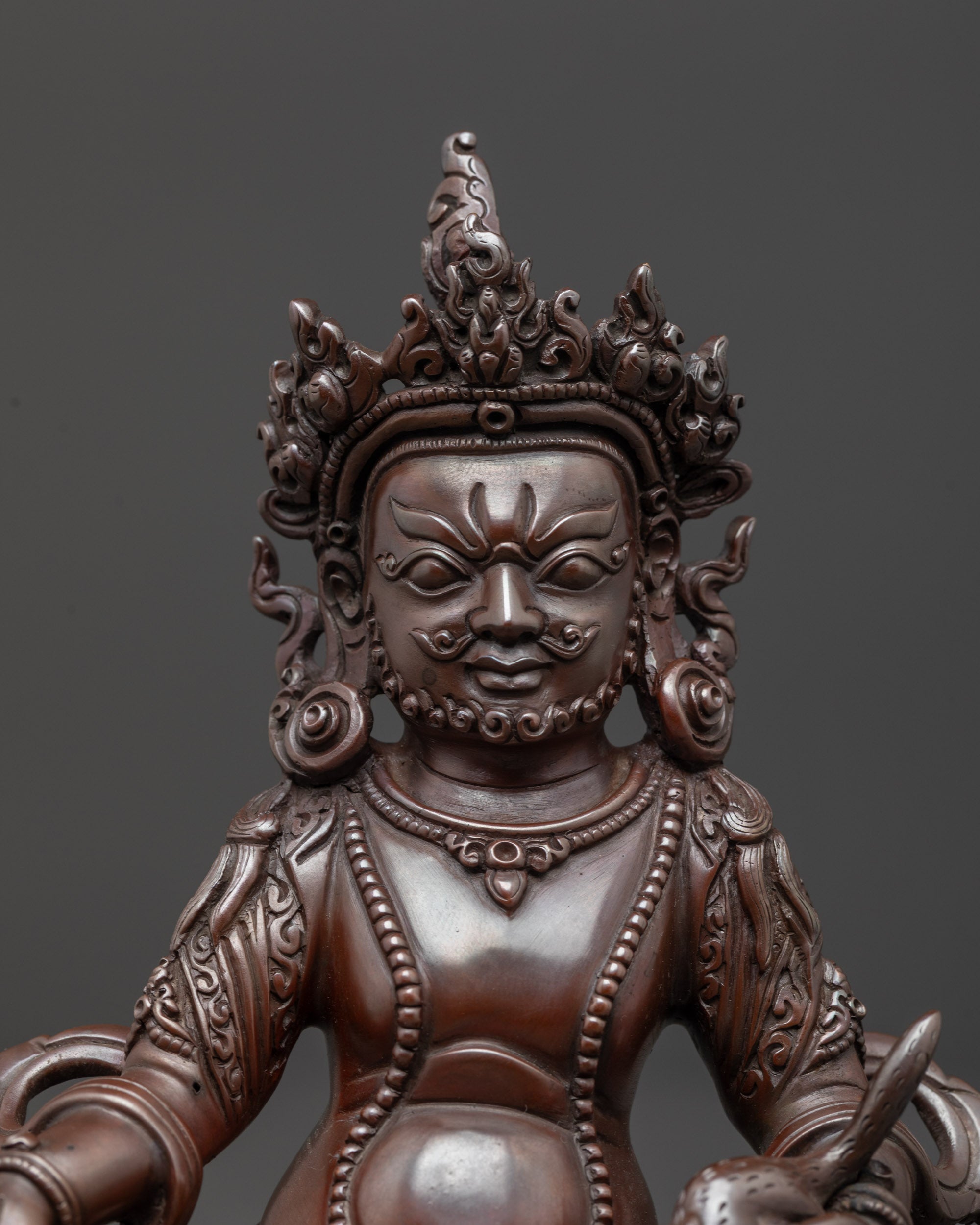 close up of Dzambhala Statue showing spitting mongoose and citron fruit details
