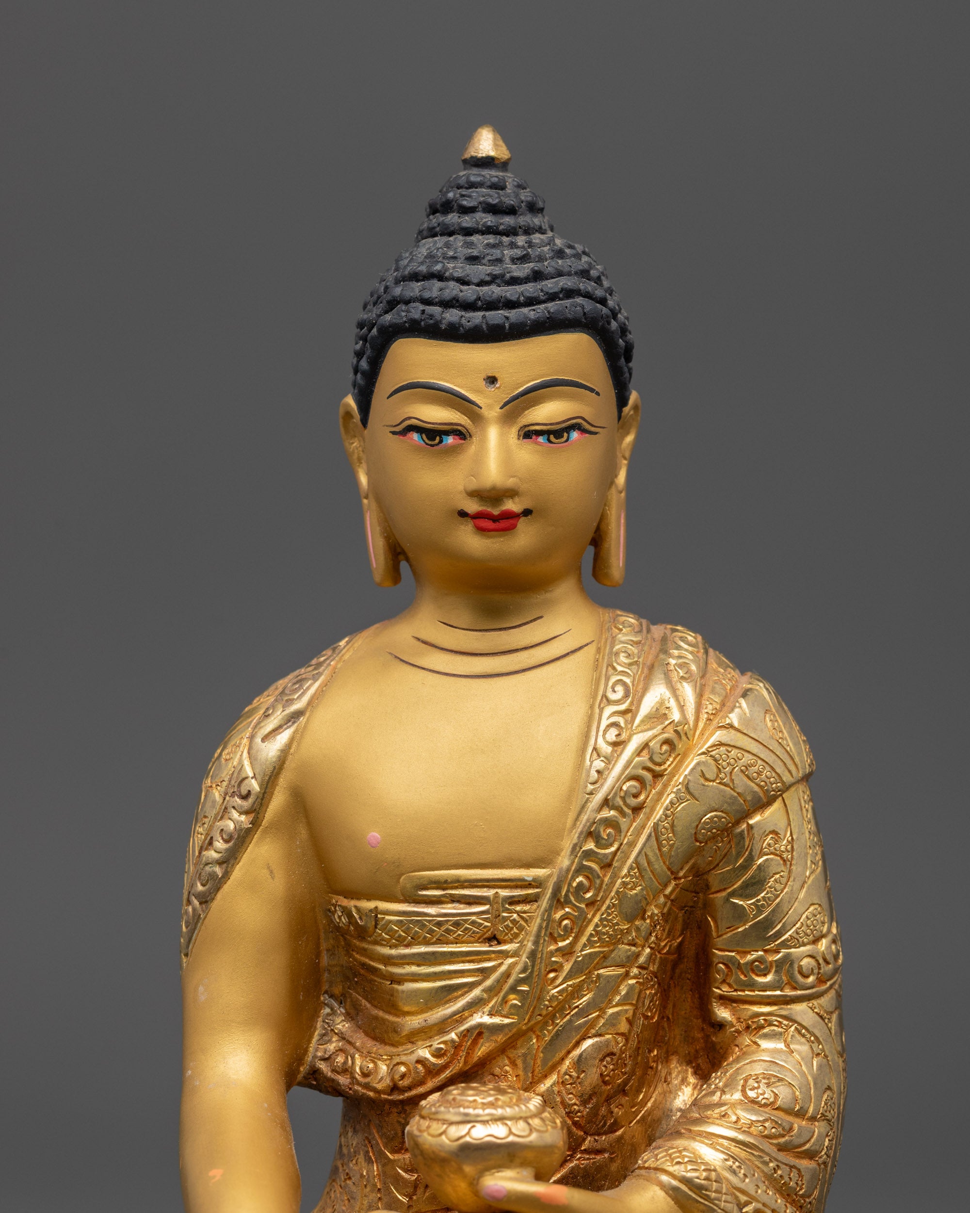 close up of Shakyamuni Buddha Statue showing gold-gilded face and intricate carved garments

