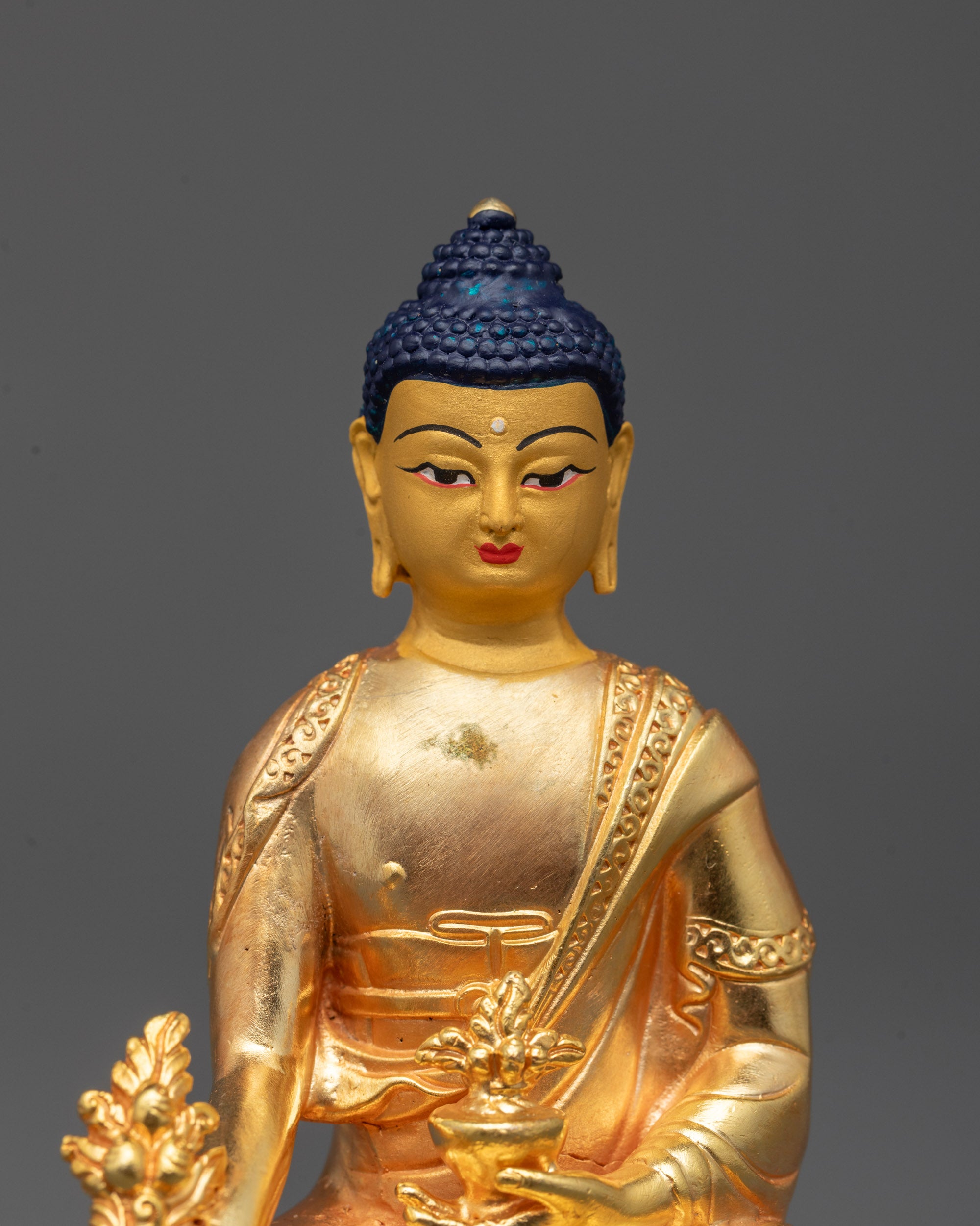 close up of gold-plated medicine buddha face showing fine electroplated copper details