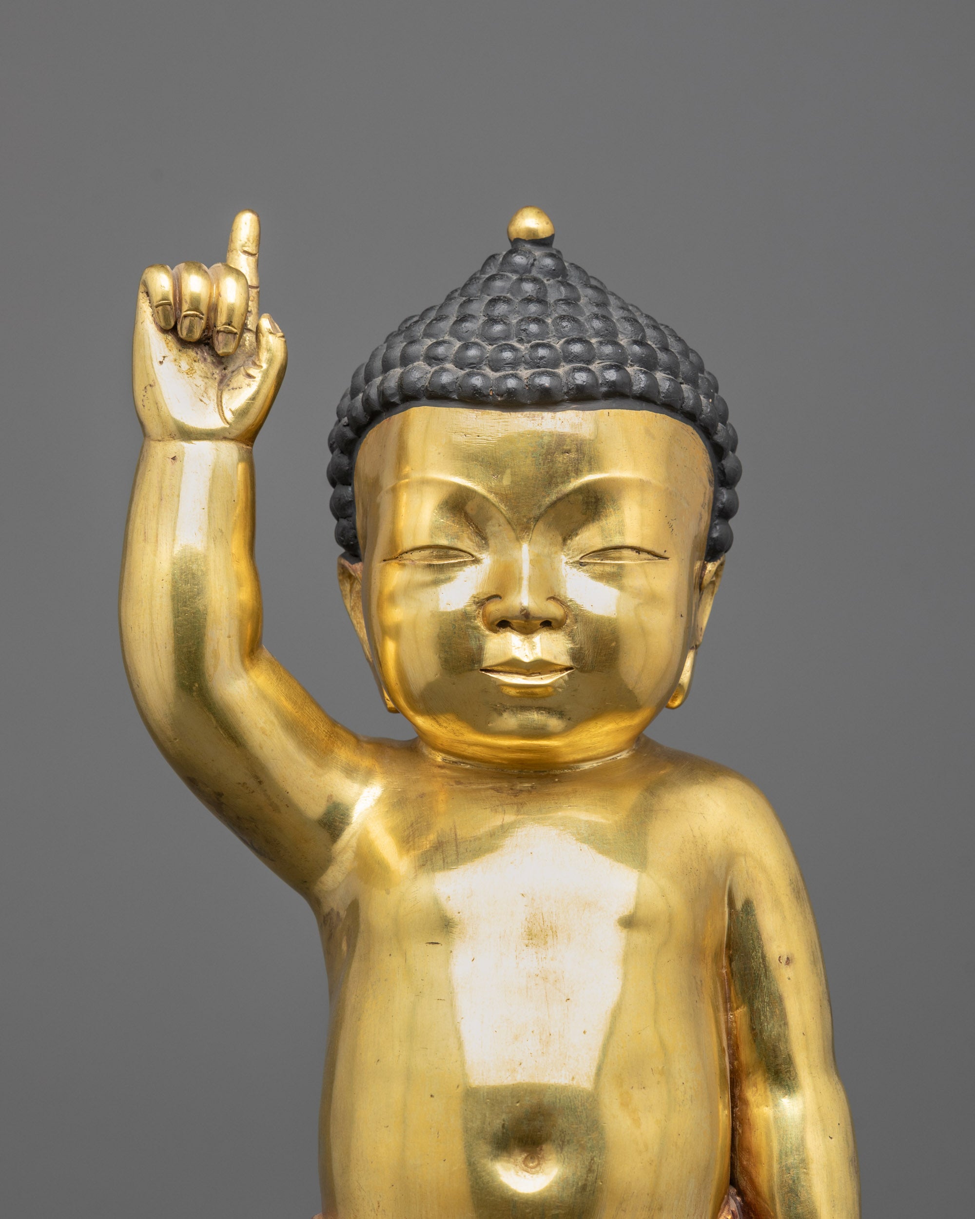 close up of gold fire-gilded face and carved robe on little buddha statue
