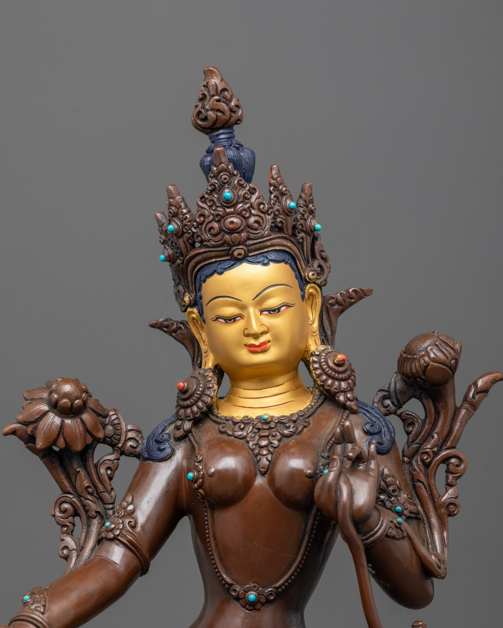 close up of green tara gold-gilded face with jeweled crown and utpala flower