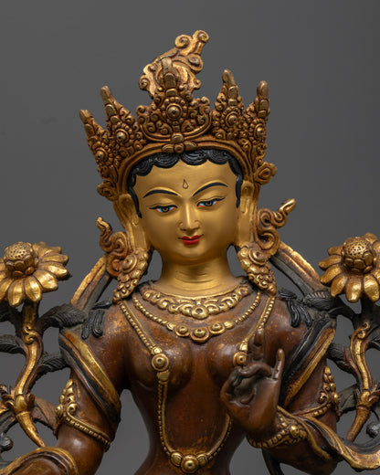 close up of green tara statue with gold-plated robe jeweled crown and serene expression