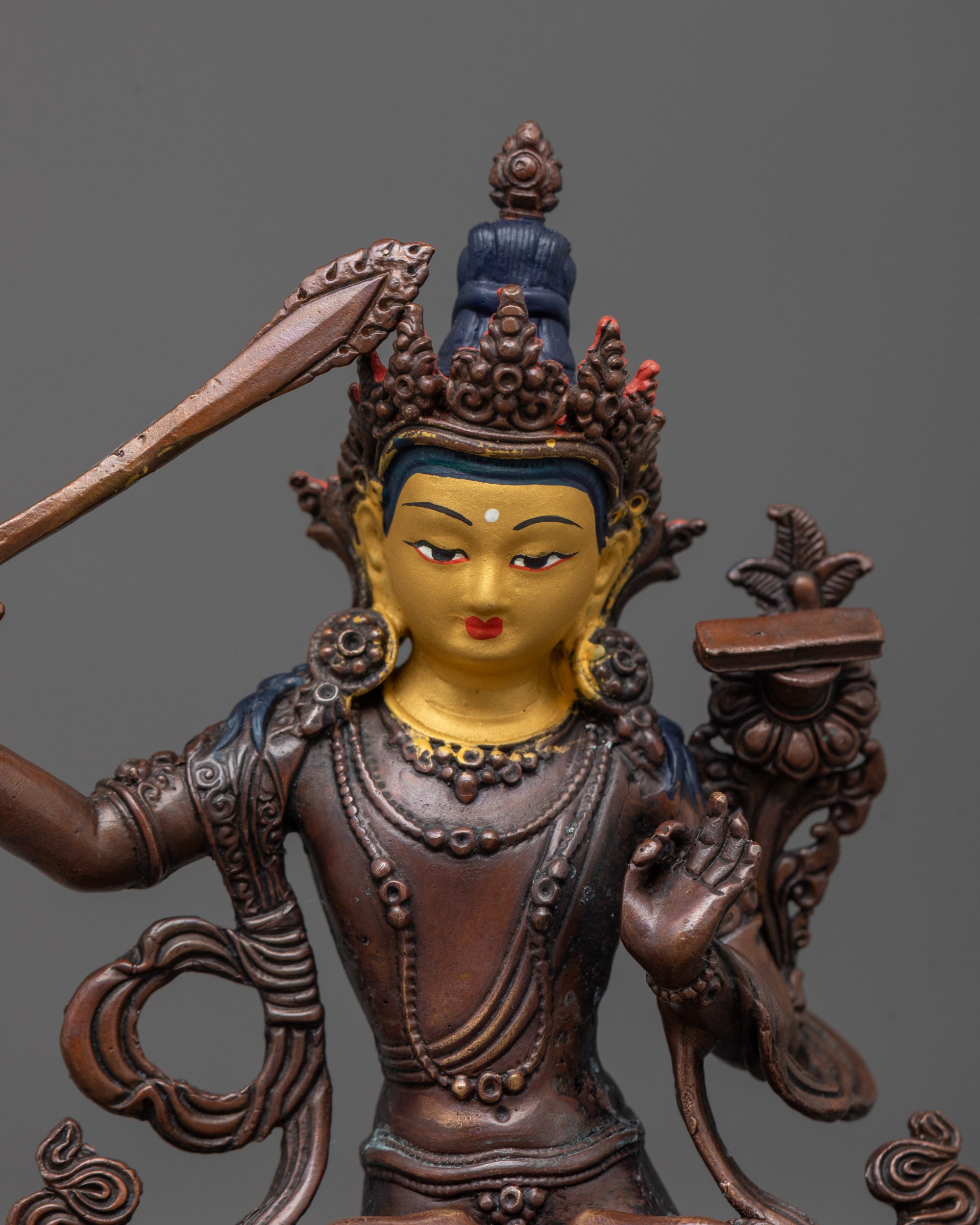 close up of manjushri bodhisattva gold-plated face and sword of wisdom in detail