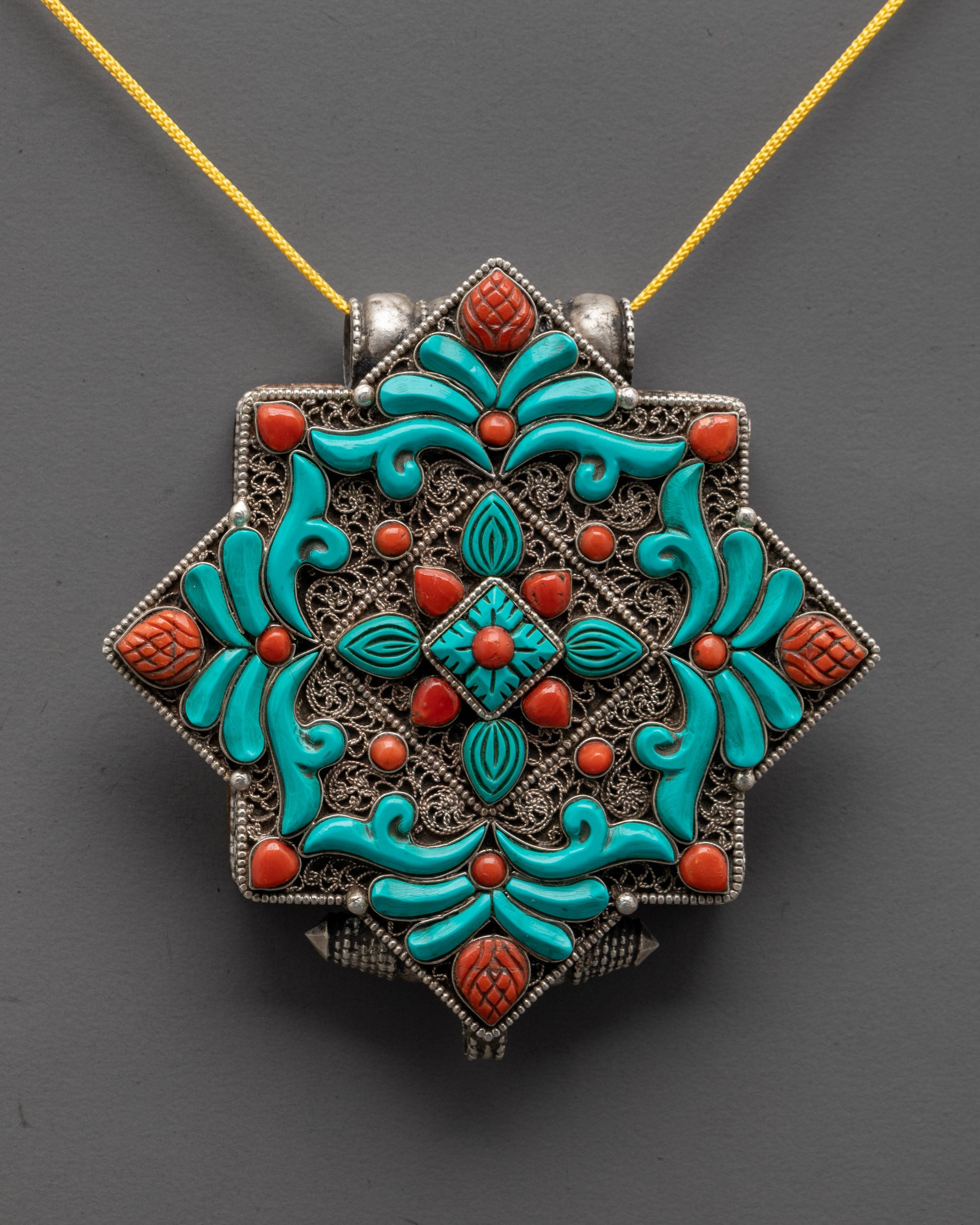 close up of tibetan locket silver filigree with coral and turquoise stones for protection