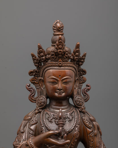 close up of vajrasattva statue showing detailed crown jewelry and serene oxidized copper face