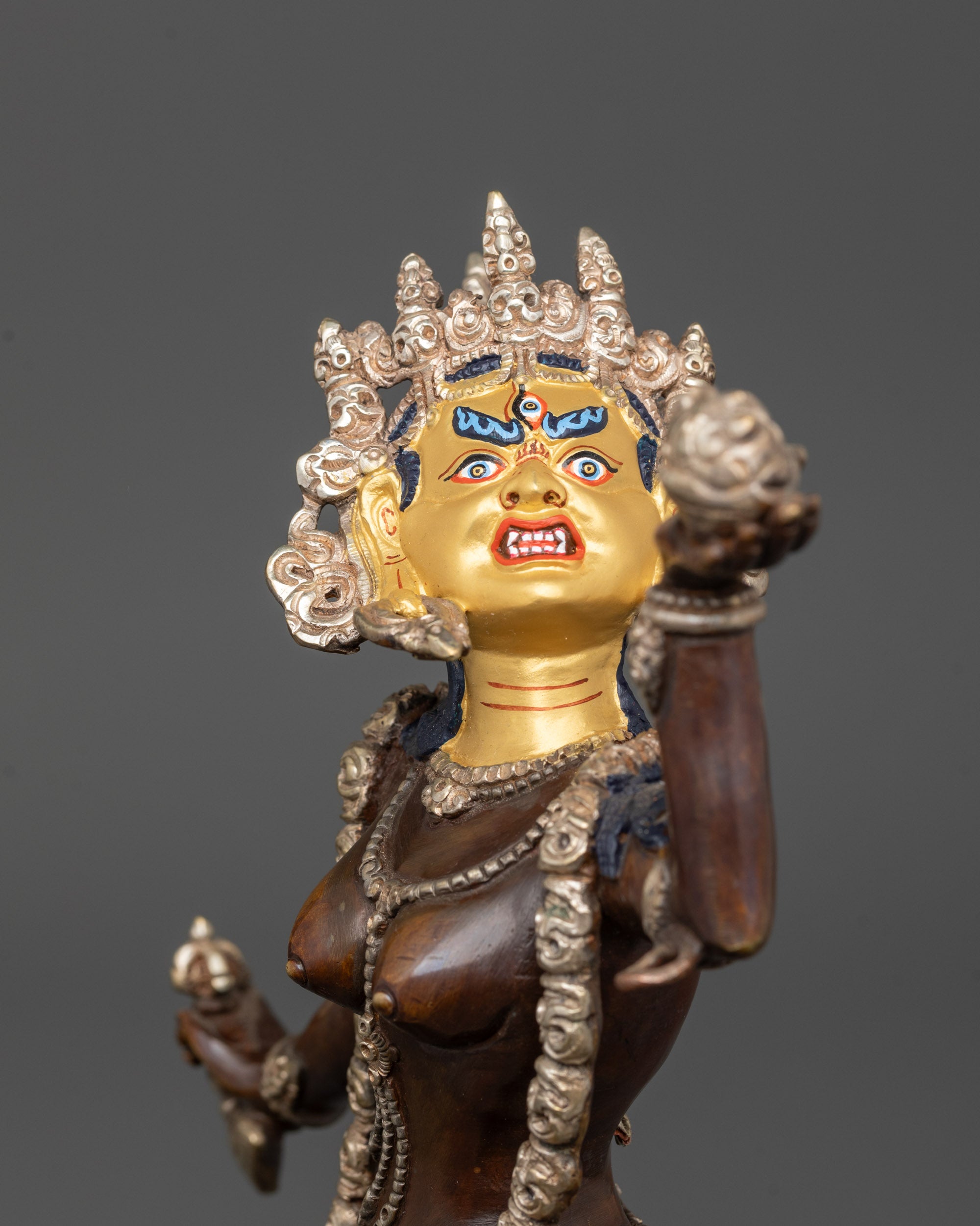 close up of vajrayogini statue showing wrathful expression and silver-plated mundamala
