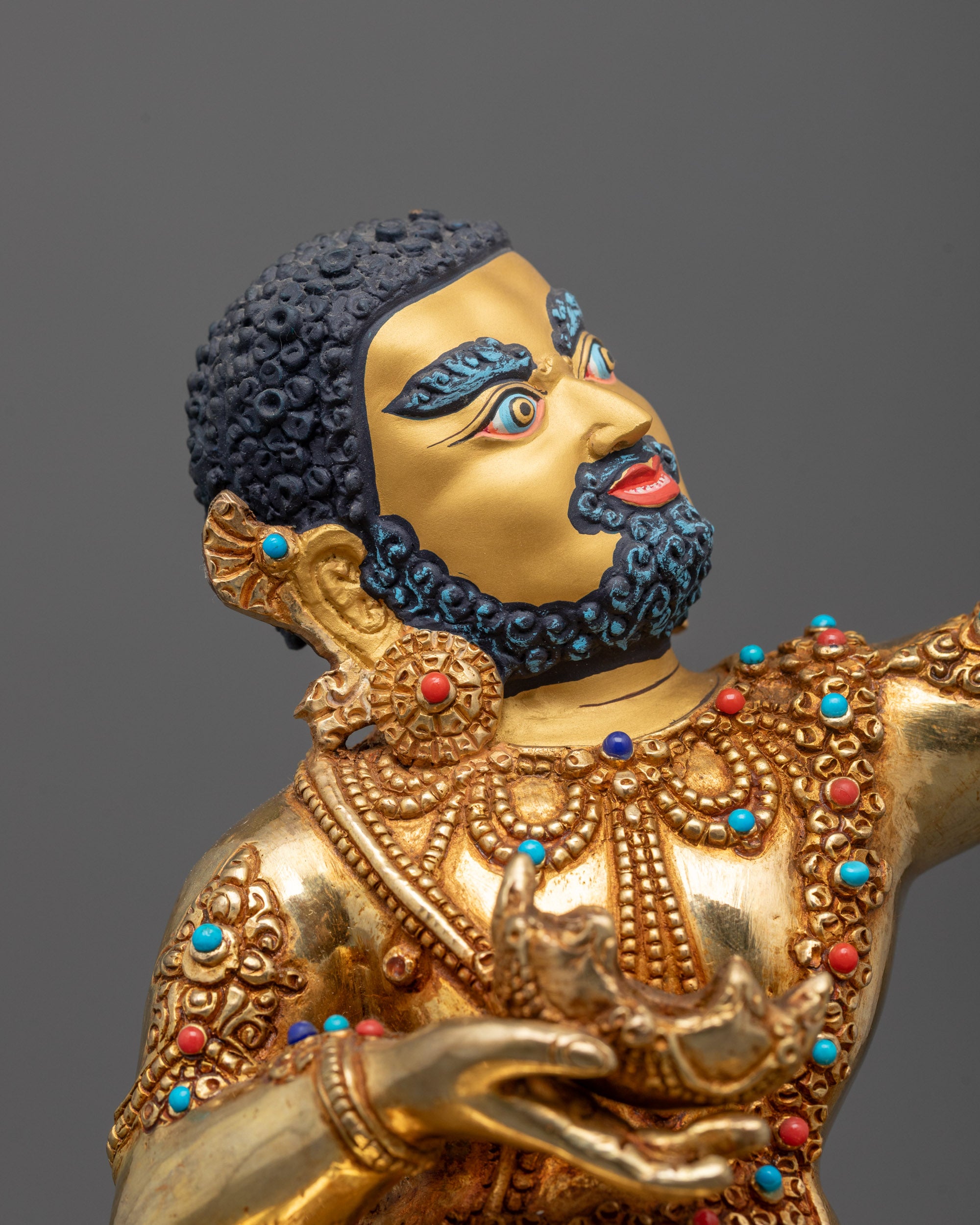 close up of virupa statue face with 24k gold gilding and skull cup detail