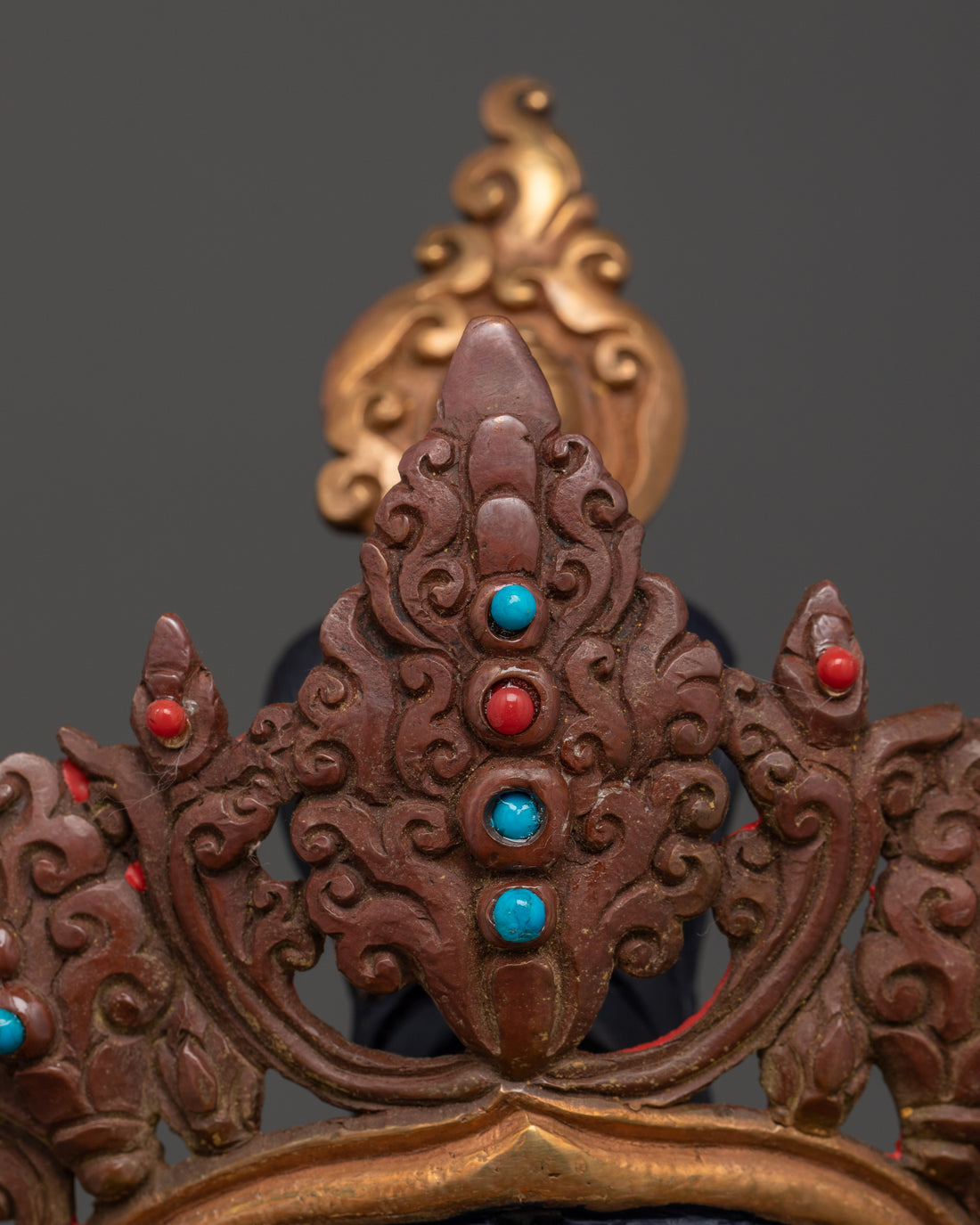 the crown of green tara statue adorned with red and turquoise gemstones