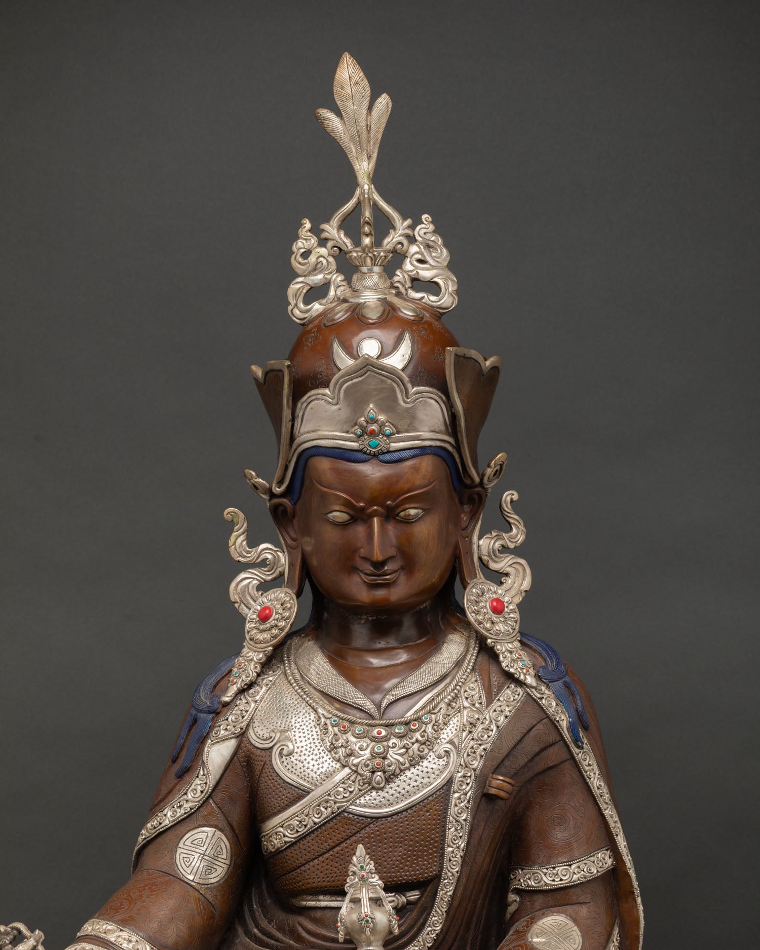 Dark brown copper Padmasambhava statue with silver-plated crown and royal robes.
