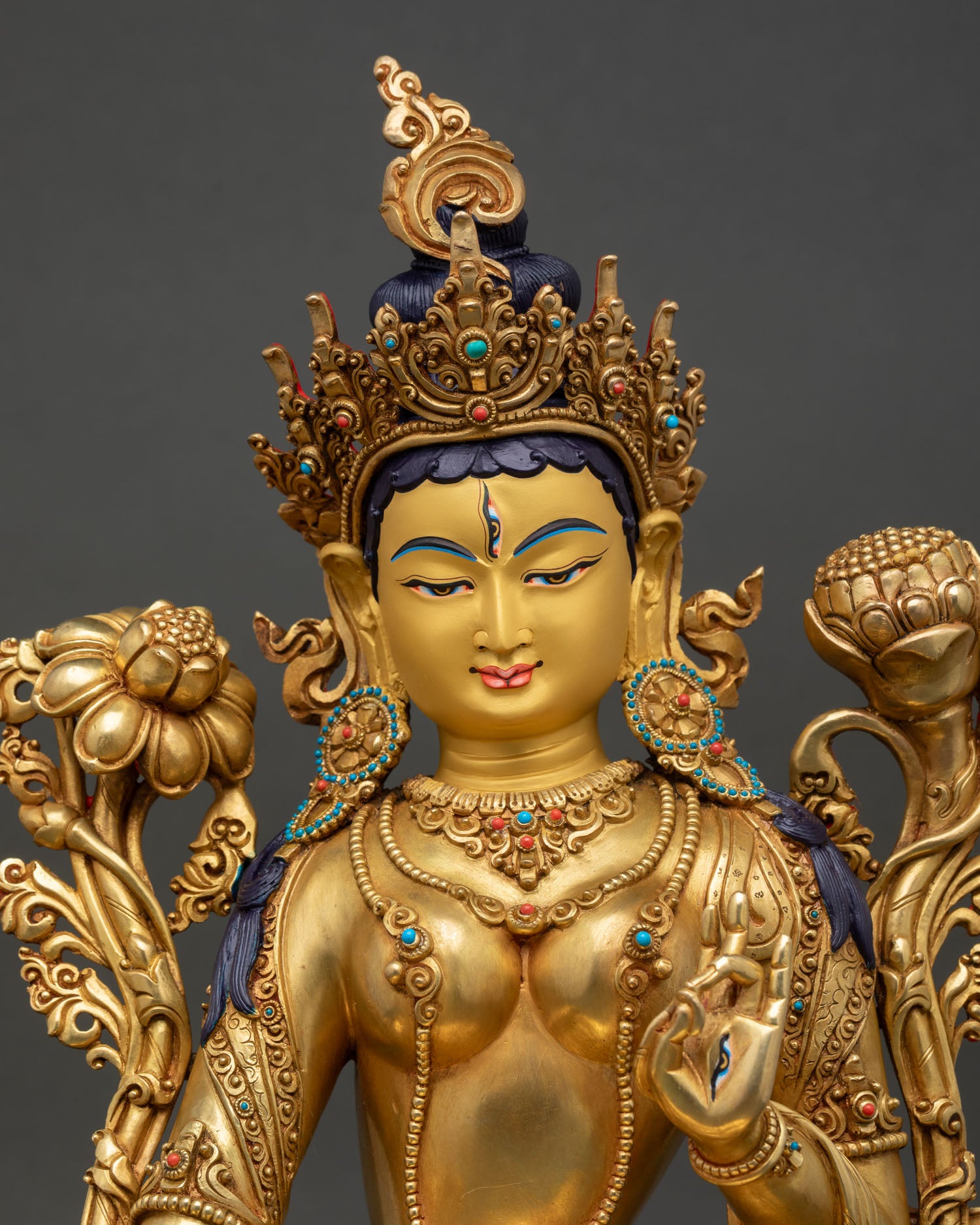 Detail view White Tara statue close up of gold painted face and seven eyes symbolizing compassion wisdom and protection